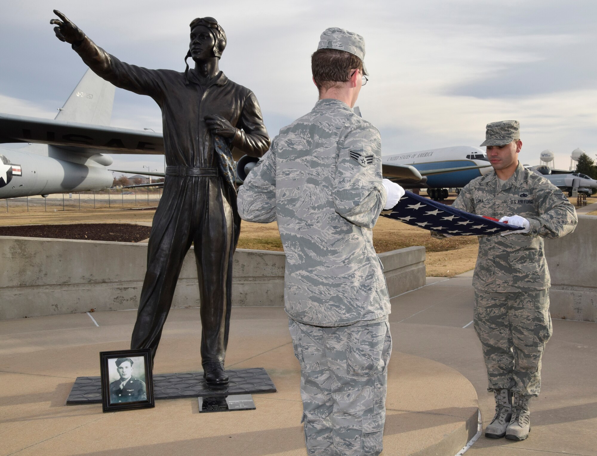 Honor Guard members, Senior Airman Joshua Meeks with the 966th Airborne Air Control Squadron (foreground) folds the 48-star flag with Staff Sgt. Kristopher Luna with the 552nd Maintenance Squadron. The Skelton family had received the flag in its original box, but it was not folded. They asked if the Honor Guard would fold it for them, thus prompting the impromptu ceremony at Memorial Park. (Air Force photo by Kimberly Woodruff)
