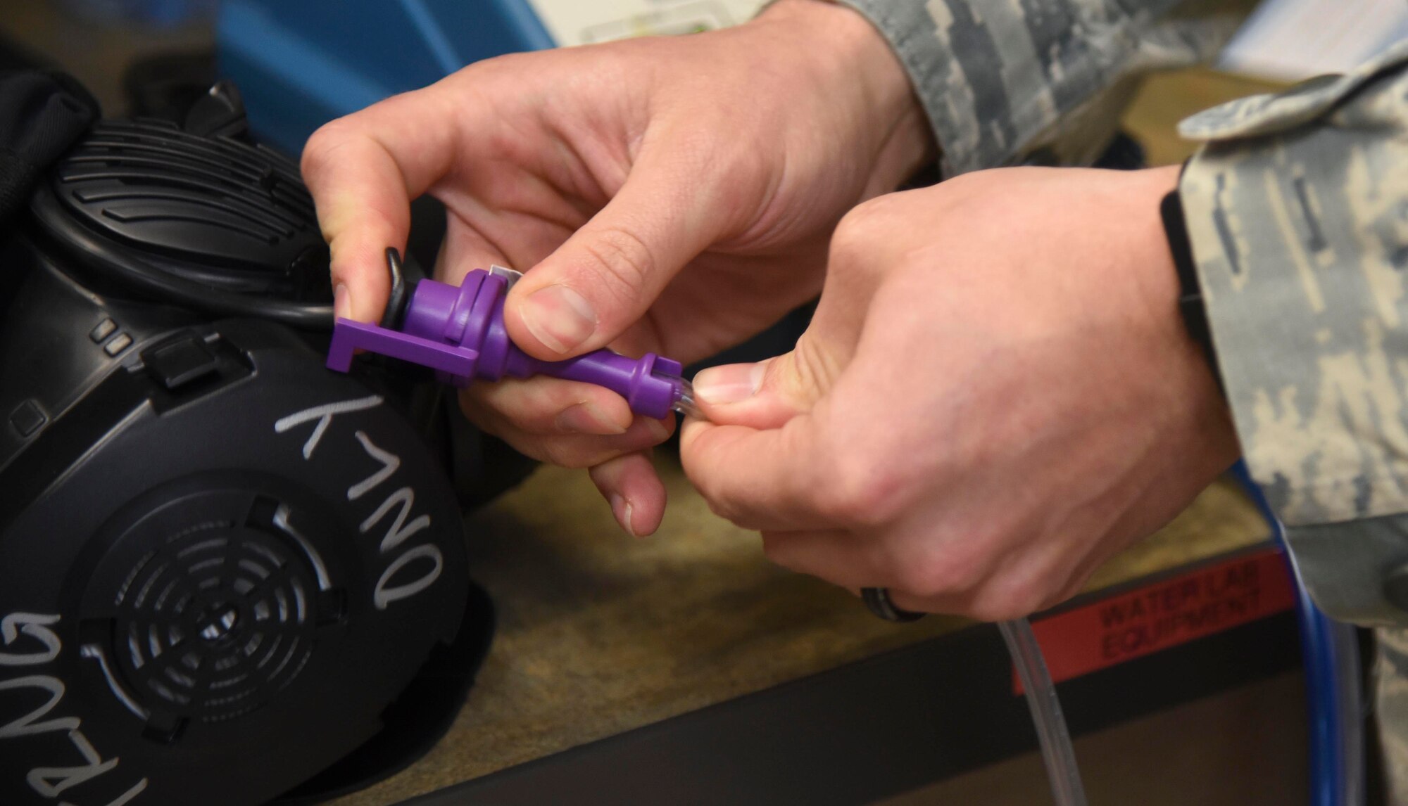 Senior Airman Ants Vahk, 92nd Aerospace Medicine Squadron bioenvironmental engineer, connects a hose to a gas mask Dec. 6, 2016 at Fairchild Air Force Base, Washington. The gas mask fit test sustains preparedness and readiness for Fairchild deployment mission. (U.S. Air Force photo/Senior Airman Nick J. Daniello)