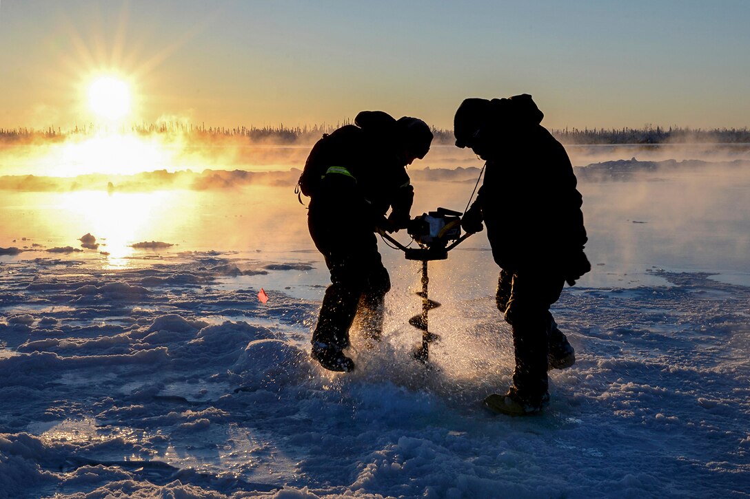 Air Force Senior Airman Carlos Aleman and Tech. Sgt. Craig Slaten drill a hole in the frozen Tanana River in Fairbanks, Alaska, Dec. 5, 2016. The airmen, both assigned to the 354th Civil Engineer Squadron, drilled in the area to build up the ice and create a stable bridge for transporting equipment and supplies. Air Force photo by Airman 1st Class Cassandra Whitman