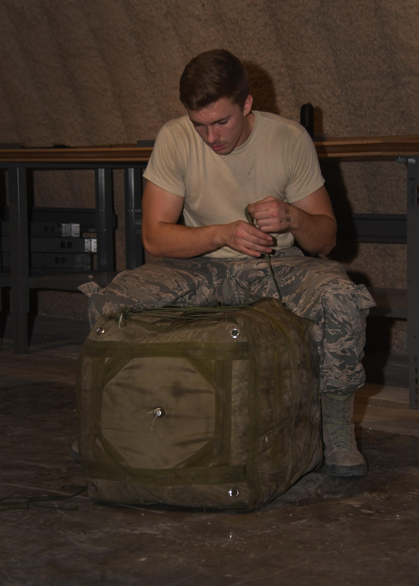 U.S. Air Force Airman 1st Class Eric Hornbeck, 379th Expeditionary Operations Support Squadron aircrew flight equipment technician, laces up a drag parachute deployment bag after a chute has been packed into it at Al Udeid Air Base, Qatar, Nov. 30, 2016. These drag chutes are used to help slow down aircraft after landing and help take strain off of the breaks. (U.S. Air Force photo by Senior Airman Miles Wilson)