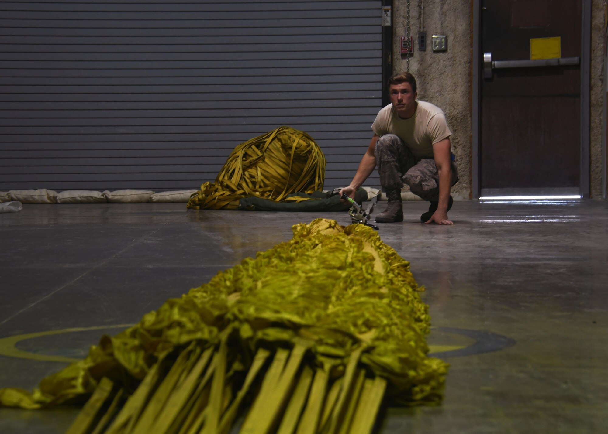 U.S. Airman 1st Class Eric Hornbeck, 379th Expeditionary Operations Support Squadron aircrew flight equipment technician, applies tension to a drag parachute so he can fold it at Al Udeid Air Base, Qatar, Nov. 30, 2016. These drag parachutes are used to help aircraft slow down after landing, and put less strain on the break systems. (U.S. Air Force photo by Senior Airman Miles Wilson)