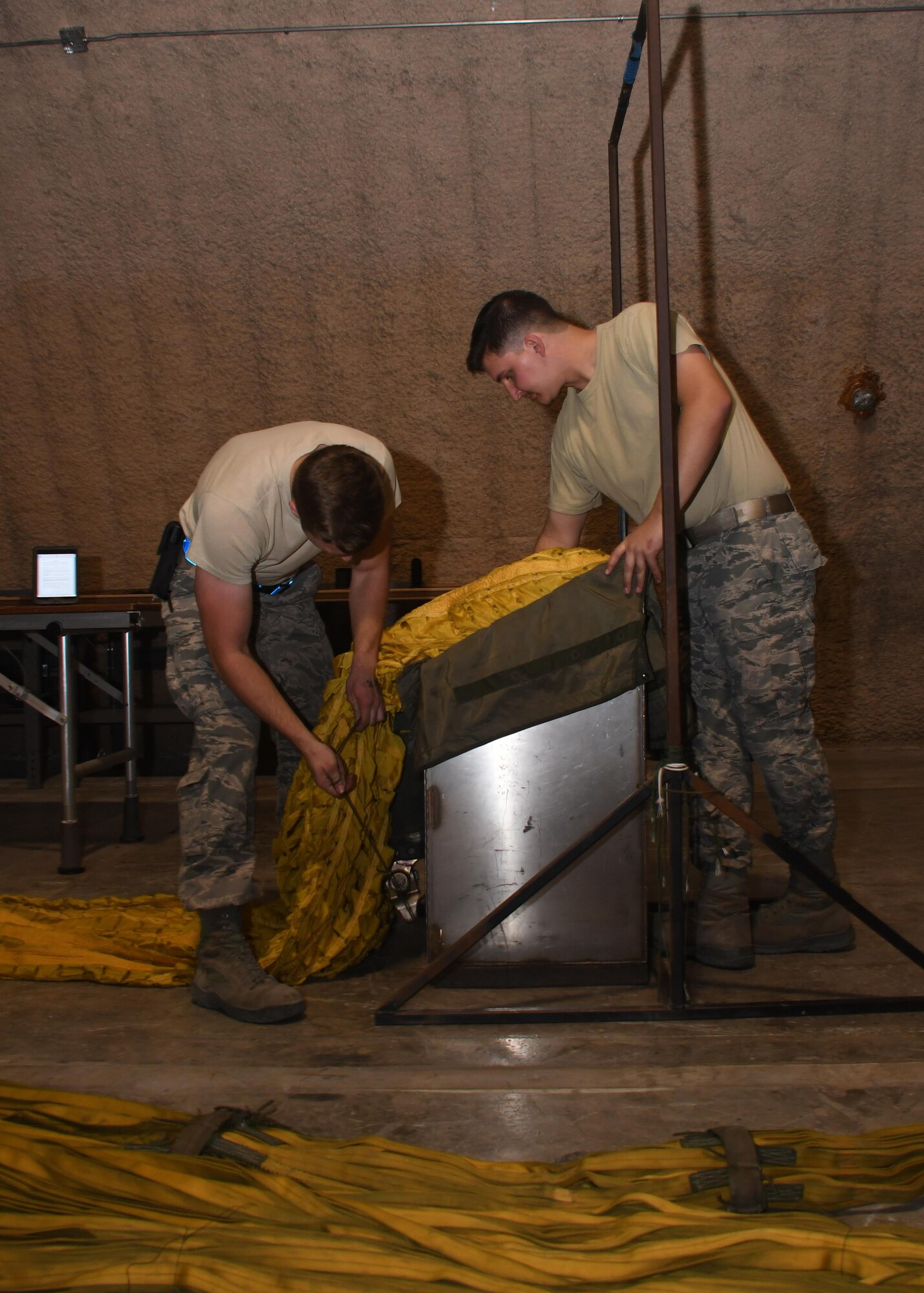 U.S. Air Force Airman 1st Class Eric Hornbeck, left, and Senior Airman Jack McDonald, right, 379th Expeditionary Operations Support Squadron aircrew flight equipment technicians, pack a drag parachute into its deployment bag at Al Udeid Air Base, Qatar, Nov. 30, 2016. These drag parachutes are deployed to help aircraft slow down, and are inspected after each use for tears, burns, broken threads or holes in the canopy. (U.S. Air Force photo by Senior Airman Miles Wilson)