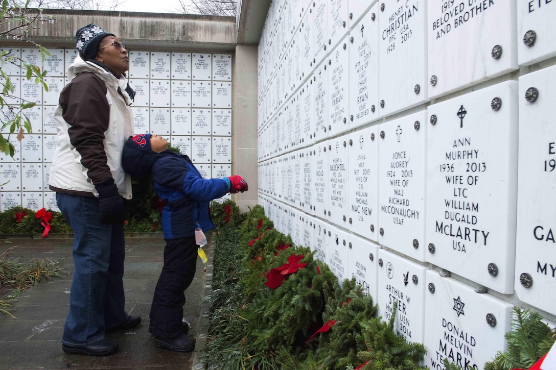 Renee Redwood, left, and James Paris, 8, read the names in a columbarium court after placing a wreath during Wreaths Across America at Arlington National Cemetery, Va., Dec. 17, 2016. Army photo by Rachel Larue