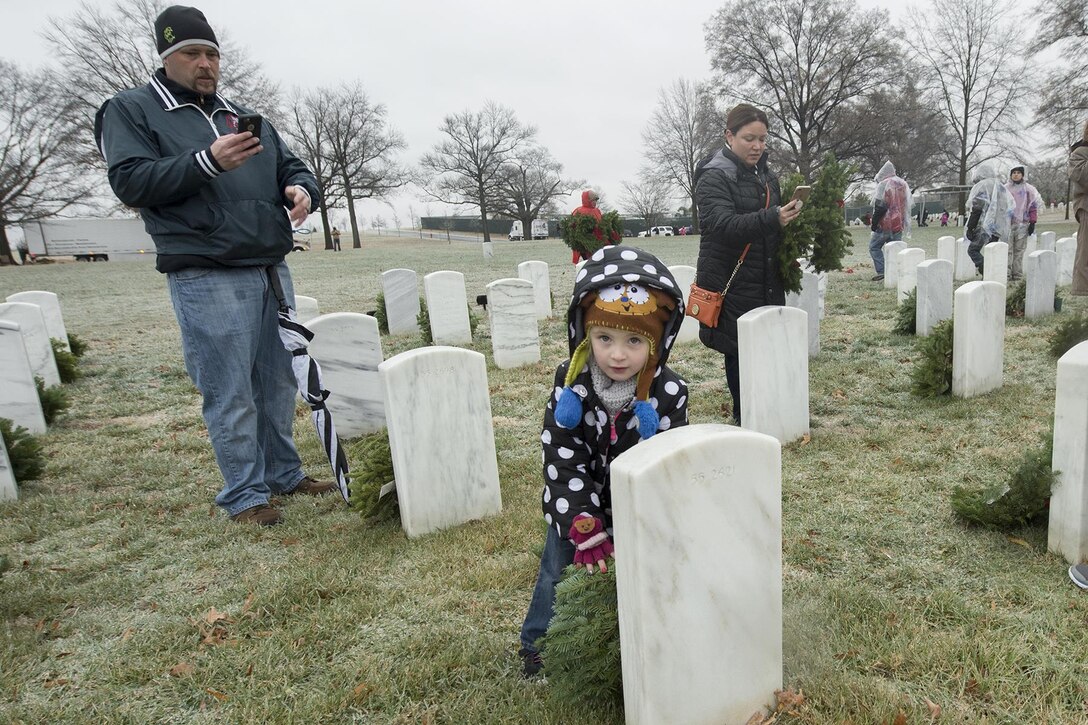 A girl helps her parents place a wreath at a family member’s headstone during Wreaths Across America at Arlington National Cemetery, Va., Dec. 17, 2016. DoD photo by EJ Hersom
