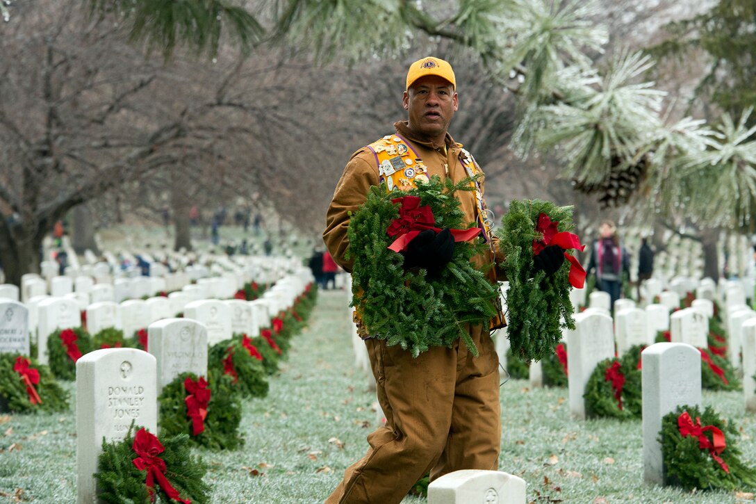 Retired Army Sgt. Roderick Harris carries wreaths to place at headstones during Wreaths Across America at Arlington National Cemetery, Va., Dec. 17, 2016. DoD photo by EJ Hersom