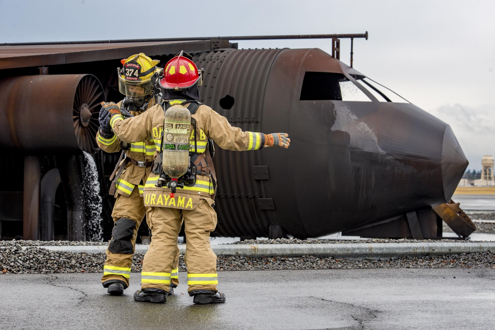 Two firefighters with the 374th Civil Engineer Squadron check each other’s personal protective equipment before a simulated aircraft fire during a training scenario on Dec. 14, 2016, at Yokota Air Base, Japan. The training helped the firefighters gain experience and build cohesiveness to work as a better team for potential real-world scenarios. (U.S. Air Force photo by Airman 1st Class Donald Hudson)