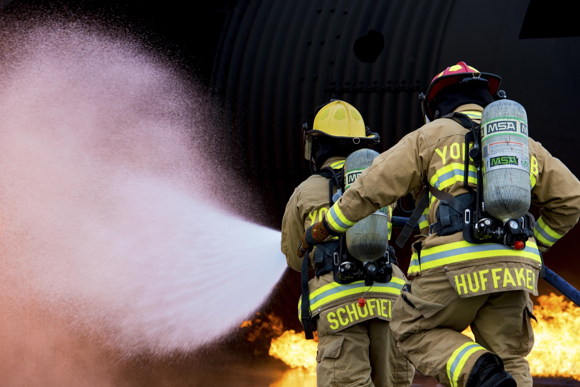 Two firefighters with the 374th Civil Engineer Squadron move towards a simulated aircraft fire during a live fire training exercise on Dec. 14, 2016, at Yokota Air Base, Japan. The training helped the firefighters gain experience and build cohesiveness to work as a better team for potential real-world scenarios. (U.S. Air Force photo by Airman 1st Class Donald Hudson)