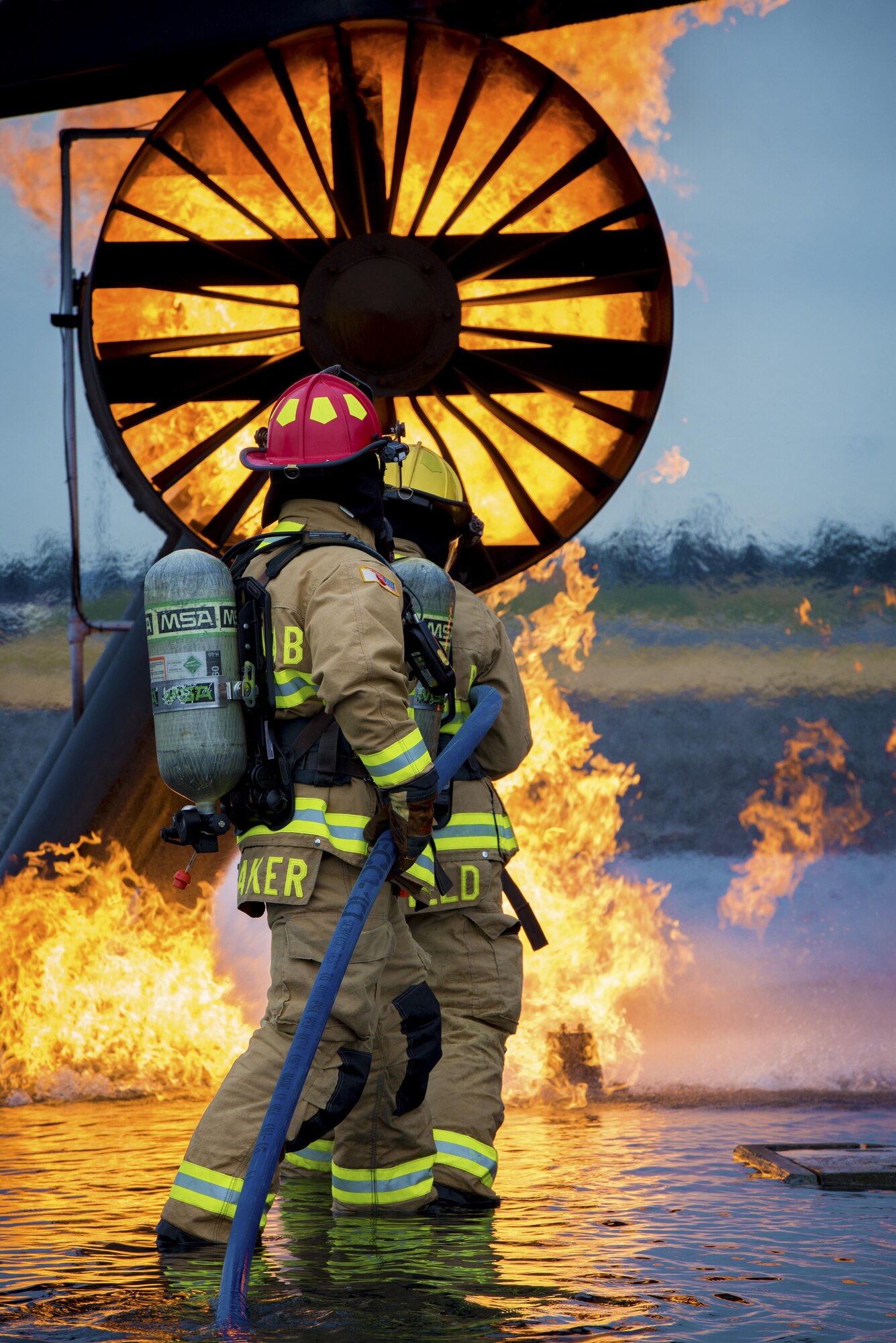 Two firefighters with the 374th Civil Engineer Squadron spray down a simulated aircraft fire during a live fire training exercise on Dec. 14, 2016, at Yokota Air Base, Japan. The live fire training consisted of a simulated aircraft in need of assistance on a runway with two engine fires and leaking fuel spreading on the ground. (U.S. Air Force photo by Airman 1st Class Donald Hudson)