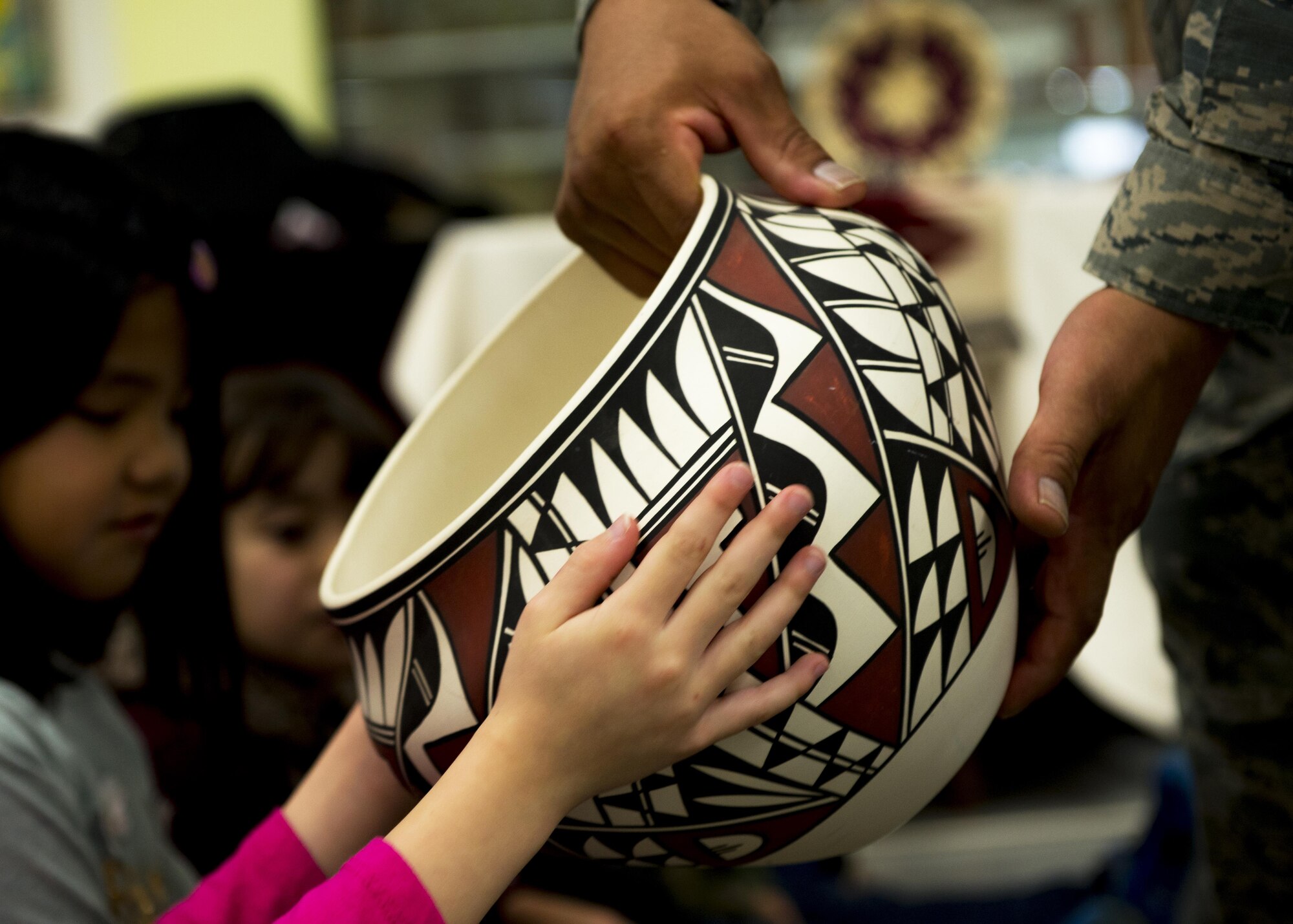 Master Sgt. Edward M. Silversmith, 374th Maintenance Squadron flight chief, lets a child feel the outside surface of traditional Navajo pottery during a National American Indian Heritage Month event at Mendel Elementary School on Nov. 30, 2016, at Yokota Air Base, Japan. Yokota’s NAIHM committee held more than 30 reading sessions at Yokota elementary schools. (U.S. Air Force photo by Airman 1st Class Donald Hudson)