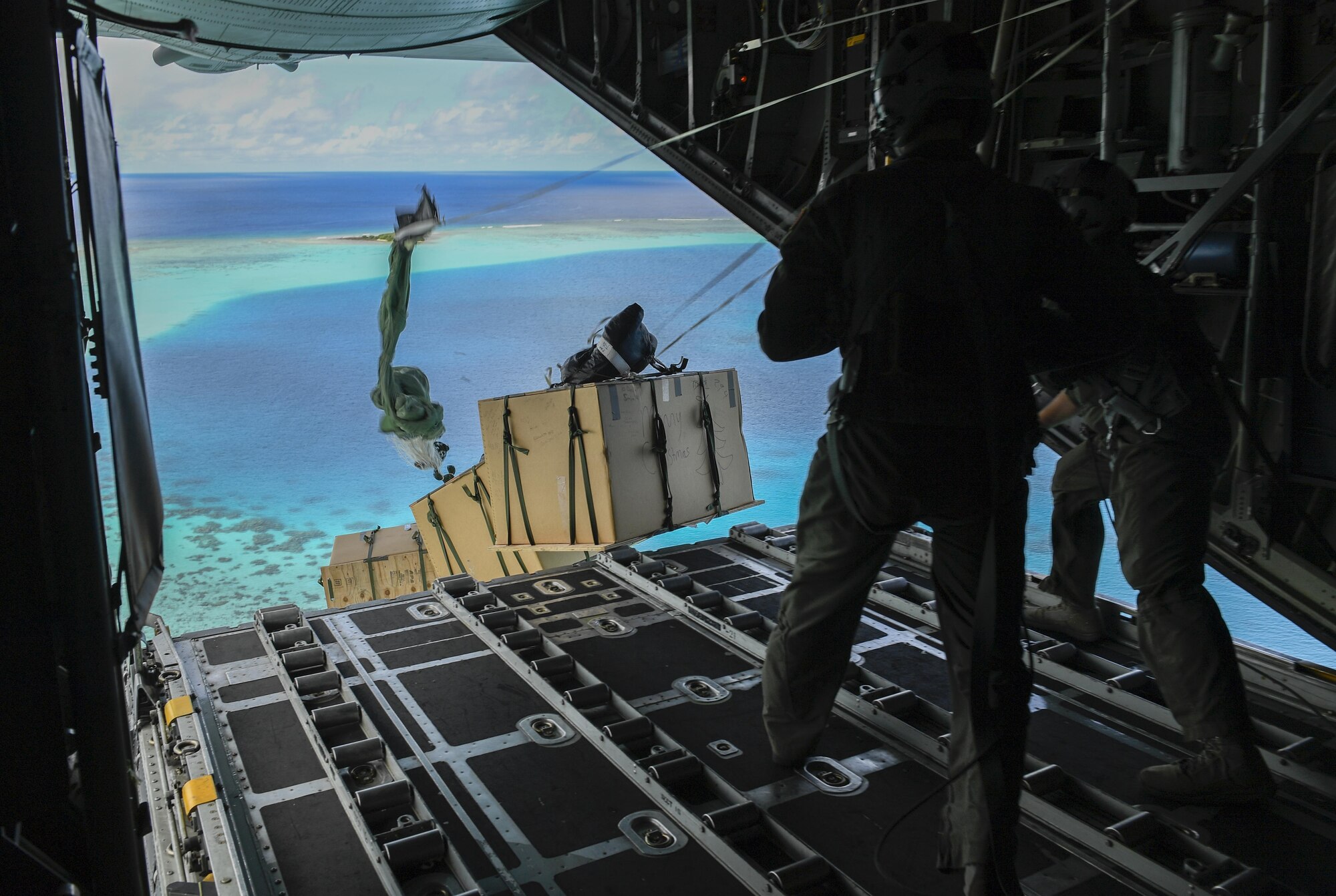 Senior Airman Nicholas Oswald, left, 36th Airlift Squadron C-130H loadmaster, and Tech. Sgt. Jonathan Lange, 36 AS C-130H Hercules instructor loadmaster, deliver bundles of donated goods to the Pacific islands during Operation Christmas Drop, Dec. 11, 2016. The operation highlights the U.S. and allied airpower capabilities to orient and respond to activities in peacetime and crisis. In addition to delivering critical supplies to those in need, Operation Christmas Drop provides specific training to U.S. and allied aircrews, enabling theater-wide airpower. (U.S. Air Force photo by Senior Airman Elizabeth Baker)