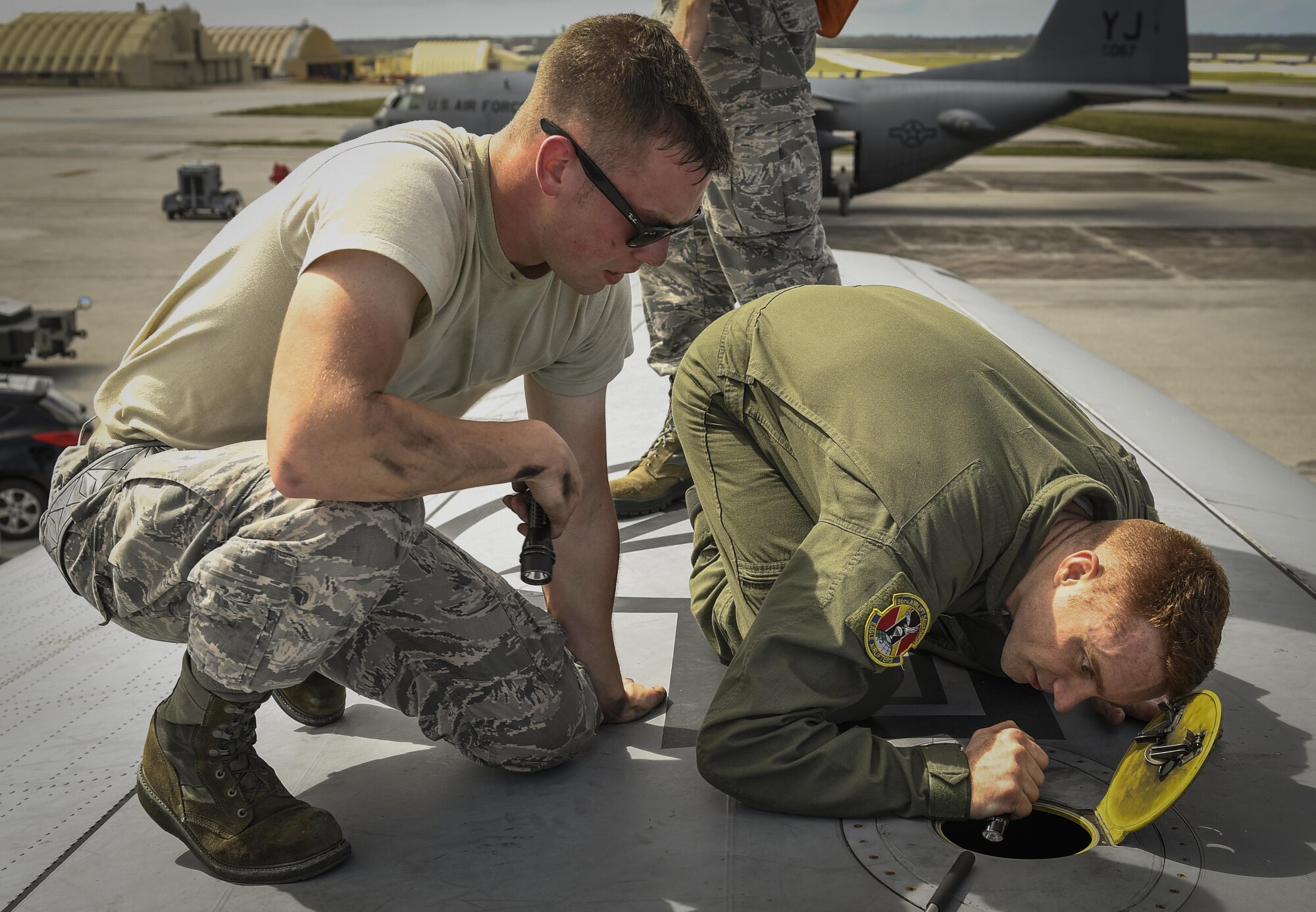 Senior Airman Benjamin Campanella, 374th Maintenance Group crew chief, and Tech. Sgt. Jonathan Lange, 36th Airlift Squadron C-130H Hercules instructor loadmaster, inspect a hydraulic leak on the wing of a C-130H Hercules during Operation Christmas Drop 2016 at Andersen Air Force Base, Guam, Dec. 10, 2016. Operation Christmas Drop highlights the U.S. and allied airpower capabilities to orient and respond to activities in peacetime and crisis. In addition to delivering critical supplies to those in need, OCD provides specific training to U.S. and allied aircrews, enabling theater-wide airpower. (U.S. Air Force photo by Senior Airman Elizabeth Baker)