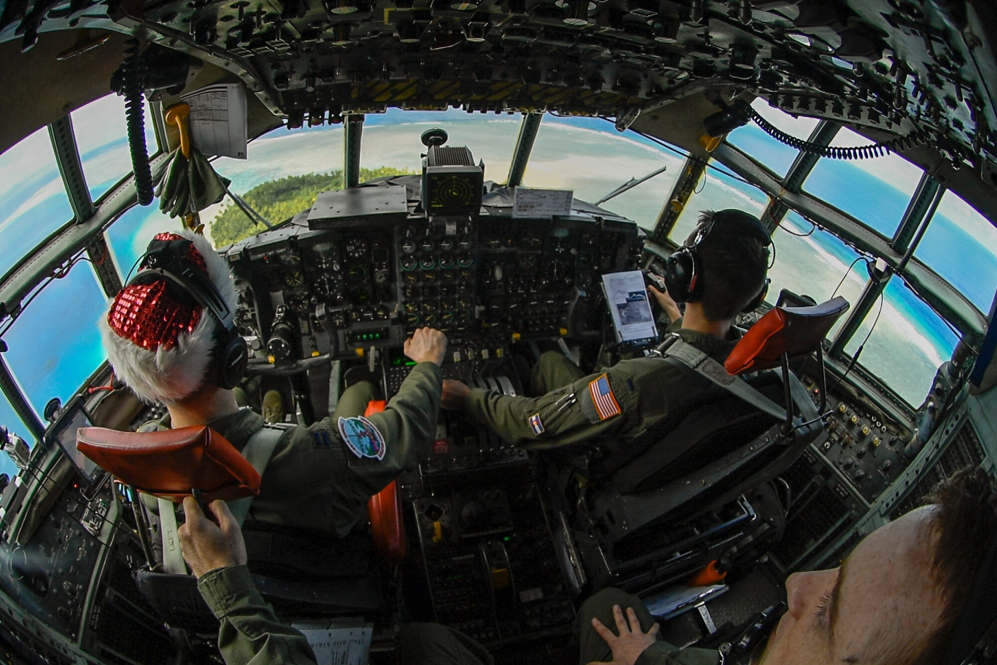 Capt. Jody Robertson, 36th Airlift Squadron flight commander, 1st Lt. Chad Moore, 36 AS pilot, and Staff Sgt. Kyle Dibble, 36 AS flight engineer, fly a C-130H Hercules over a Pacific island during Operation Christmas Drop, Dec. 11, 2016. The operation highlights the U.S. and allied airpower capabilities to orient and respond to activities in peacetime and crisis. In addition to delivering critical supplies to those in need, OCD provides specific training to U.S. and allied aircrews, enabling theater-wide airpower. (U.S. Air Force photo by Senior Airman Elizabeth Baker)
