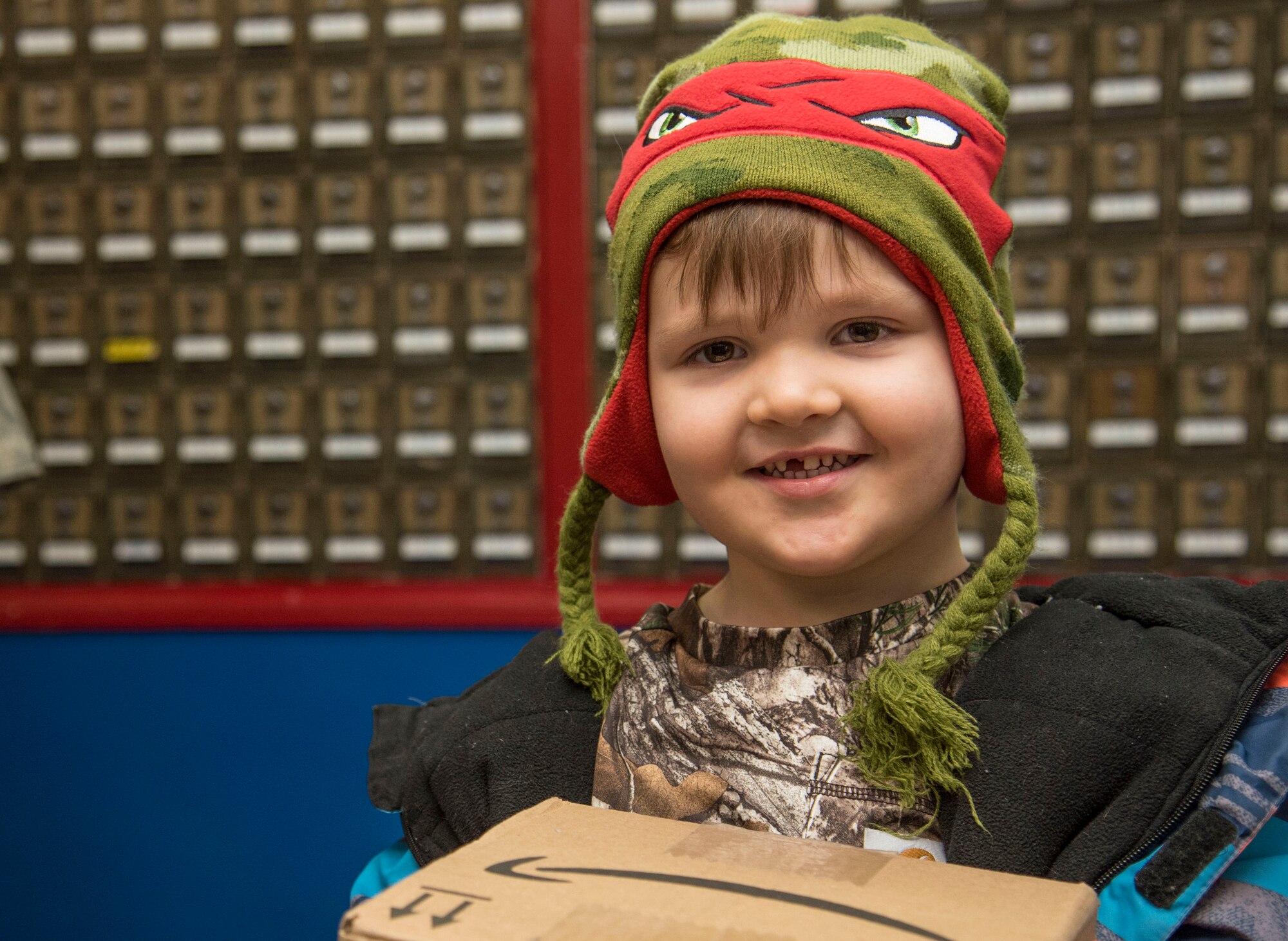 Conner Strickland, son of U.S. Air Force Staff Sgt. Jeremiah Strickland, a 35th Security Force Squadron defender, smiles as he holds his package at Misawa Air Base, Japan, Dec. 12, 2016. Once a package arrives, it is scanned into the post office inventory and a notification slip is printed and placed into the correct inbox. Personnel have 15 days to pick up their package or else it will be returned to the sender. (U.S. Air Force photo by Airman 1st Class Sadie Colbert)