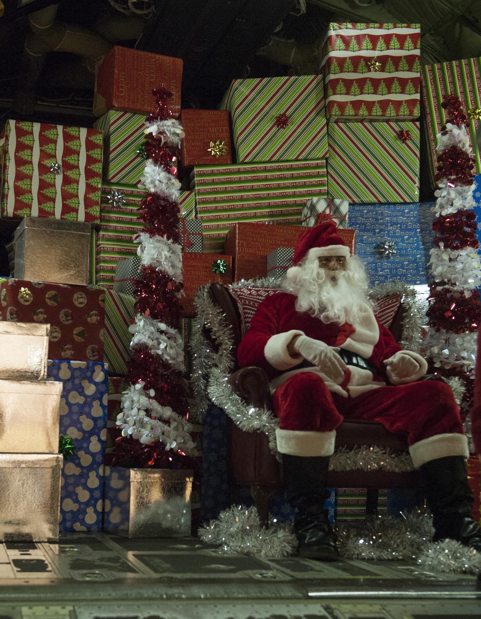 Santa Claus sits in front of stacked presents in the back of a C-130J Super Hercules during a Christmas event at Ramstein Air Base, Germany, Dec. 16, 2016. Santa Claus took to visiting Ramstein to give presents and spread holiday cheer to the largest community of U.S. children outside of the U.S. (U.S. Air Force photo by Airman 1st Class Lane T. Plummer)