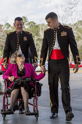 Two officers escort a guest during the Marine Corps Air Station Beaufort Officers’ Spouses’ Club’s senior citizen’s tea aboard MCAS Beaufort, Dec. 11. MCAS Beaufort holds the annual event to honor and serve the senior citizens of the Beaufort area. This year marked the 47th  year of the annual tea. Many of the senior citizens who attended are former service members or spouses of former service members.