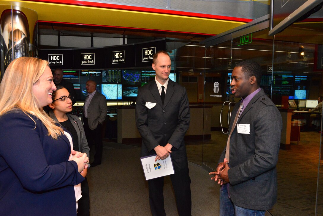 Kimberly Whiting, left, a manager of network operations with Union Pacific, speaks to Staff Sgt. Lauren Morales, command chief's executive with the 557th Weather Wing, Maj. Brian Yates, chief of the 557th WW commanders action group and Master Sgt. Jawarski Seals, 557th WW first sergeant, about the Union Pacific mission and training requiremetns at the Harriman Dispatching Center in Omaha, Neb., Dec. 16, 2016. Union Pacific adopted several 557th WW for the holiday season, providing presents for families in need. 