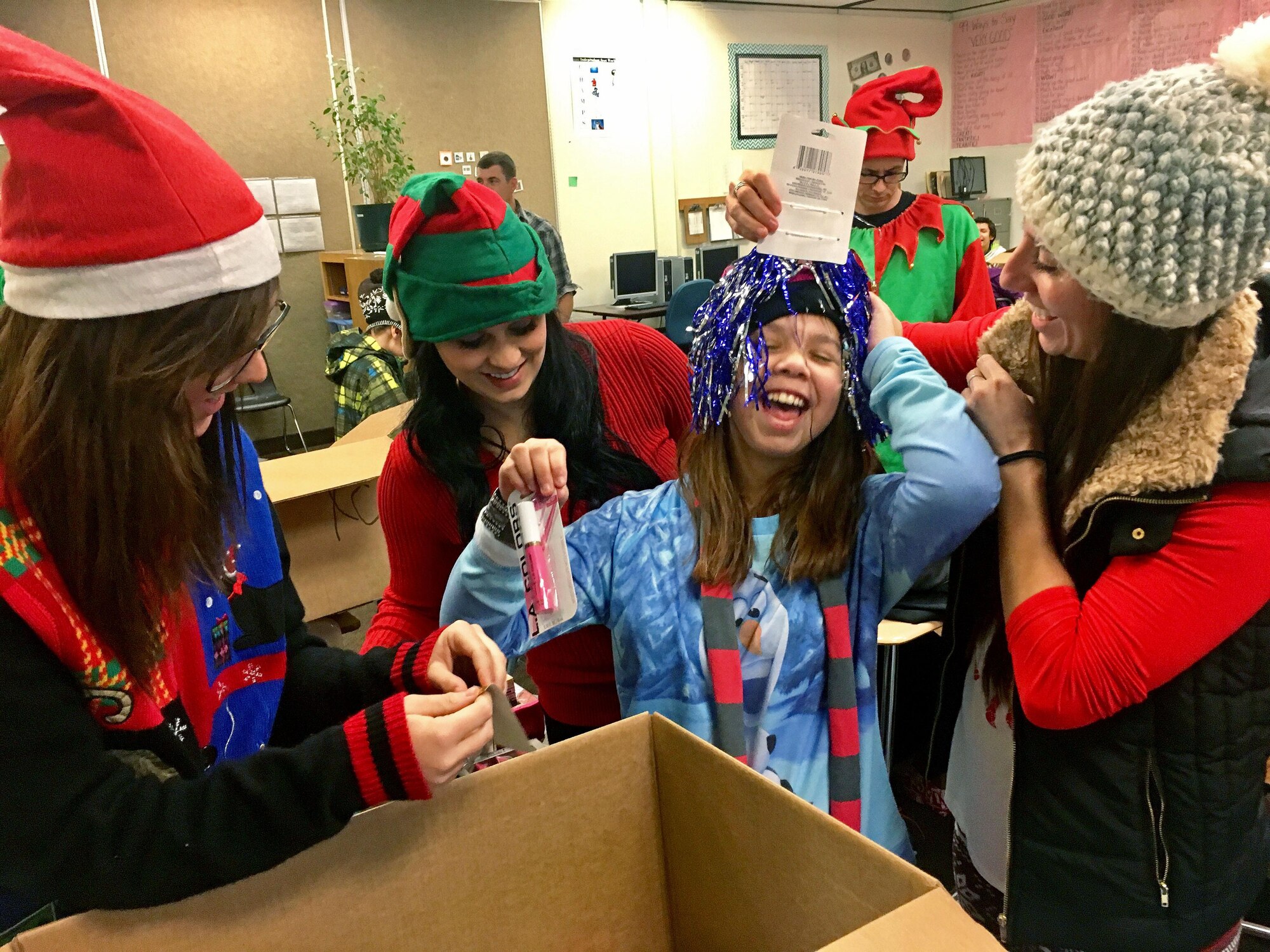 Senior Airman Kassidi Nudd, Staff Sgt. Brandey Faurot, and Tech. Sgt. Sara Kunze, from the 67th Aerial Port Squadron, help Auri open presents during a Christmas party for students with special needs at Mound Fort Junior High in Ogden Dec. 16. The 67th APS has hosted the party annually for nearly 30 years, providing gifts, clothes, and hygiene items. (U.S. Air Force photo)