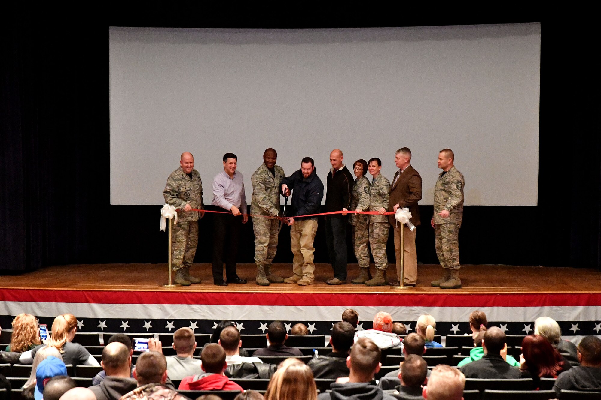 Leaders from the 319th Air Base Wing join with Army & Air Force Exchange Service leaders to cut the ribbon and reopen the base theater on Grand Forks Air Force Base, N.D., Dec. 16, 2016. Renovations to the theater included technological updates the point-of-sale systems, the projection system and the sound system. (U.S. Air Force photo by Airman 1st Class Elijaih Tiggs)