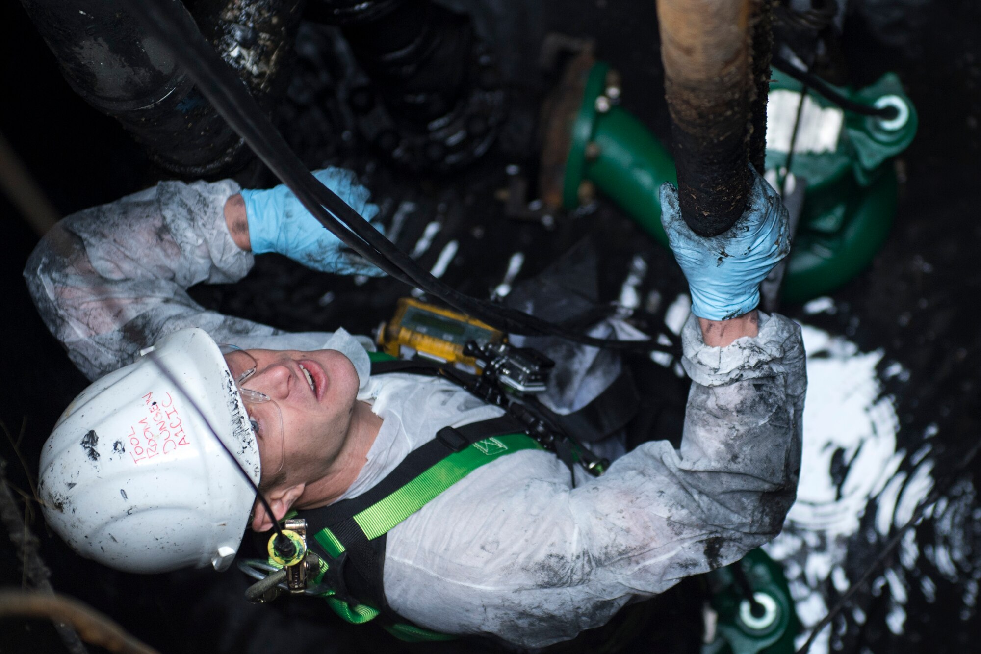 Senior Airman Justin Barrett, 11th Civil Engineer Squadron water and fuel system maintenance journeyman, yells up to the crew on top while replacing a pair of lift station pumps inside a sewage containment hole at Joint Base Andrews, Md., Dec. 13, 2016. This particular hole supports hangars on the east side of base. (U.S. Air Force photo by Senior Airman Philip Bryant)