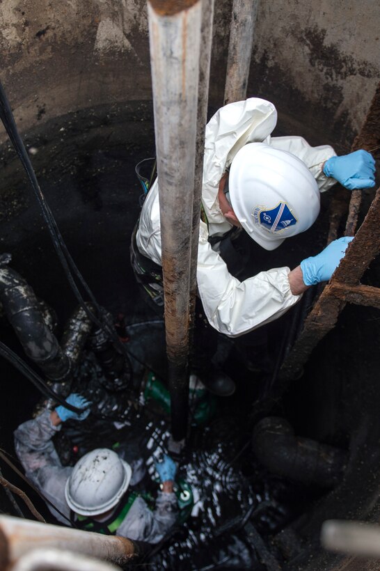 Col. E. John Teichert, right, 11th Wing and Joint Base Andrews commander, descends into a sewage containment hole to Senior Airman Justin Barrett, left, 11th Civil Engineer Squadron water and fuel system maintenance journeyman, in order to replace a pair of lift station pumps at Joint Base Andrews, Md., Dec. 13, 2016. The sewage containment hole is approximately 25 feet deep and 7 feet wide. (U.S. Air Force photo by Senior Airman Philip Bryant)