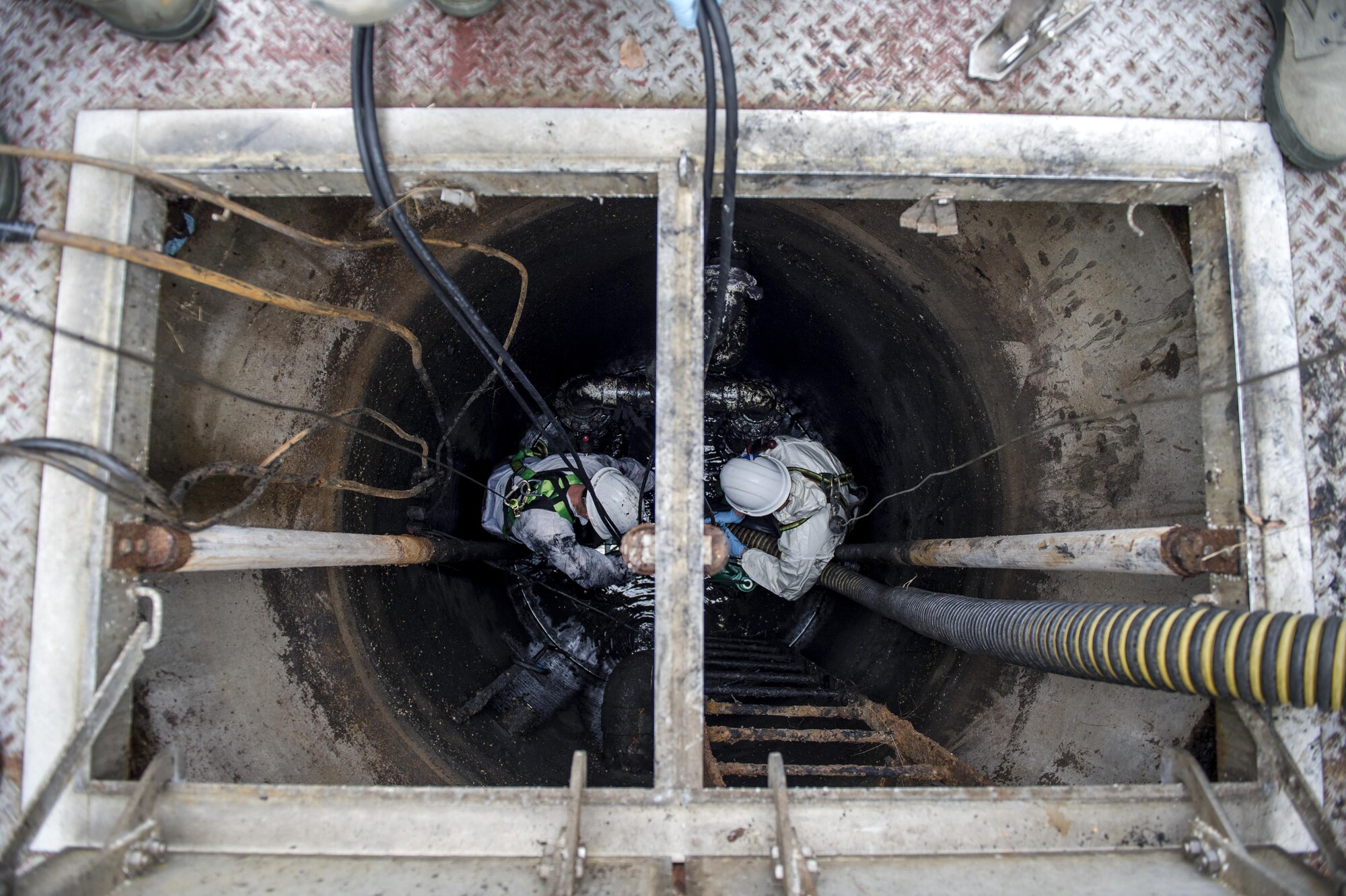 Col. E. John Teichert, right, 11th Wing and Joint Base Andrews commander, pumps out sewage water from the bottom of a sewage containment hole with Senior Airman Justin Barrett, left, 11th Civil Engineer Squadron water and fuel system maintenance journeyman, in order to replace a pair of lift station pumps at Joint Base Andrews, Md., Dec. 13, 2016. Sewage water at the bottom needs to be pumped out through a large vacuum before the lift station pumps are put in. (U.S. Air Force photo by Senior Airman Philip Bryant)