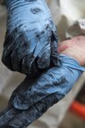 Senior Airman Justin Barrett, 11th Civil Engineer Squadron water and fuel system maintenance journeyman, removes his gloves after replacing a pair of lift station pumps at Joint Base Andrews, Md., Dec. 13, 2016. Plastic gloves, waders, protective suits, eye protection, lift harnesses and hardhats are worn to ensure safety on the job. (U.S. Air Force photo by Senior Airman Philip Bryant)