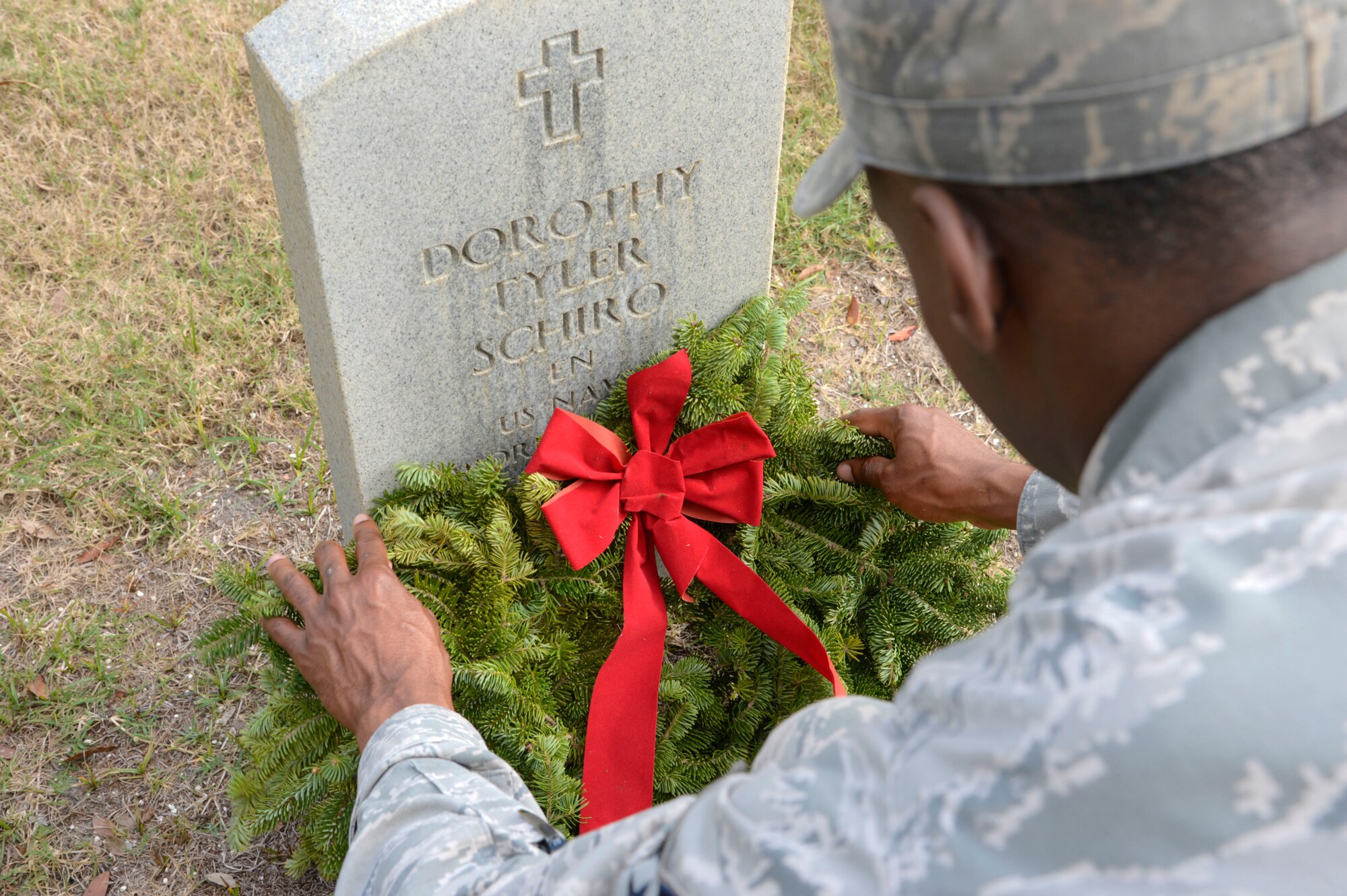 Senior Airman Vernon Fowler, photojournalist with the 6th Air Mobility Wing Public Affairs office, adjusts a wreath at Florida National Cemetery in Bushnell, Fla., Dec. 17, 2016. Airmen from MacDill Air Force Base participated in the day of honor at the 11th Annual Wreath Laying Ceremony at Florida National Cemetery. (U.S. Air Force photo by Senior Airman Tori Schultz)