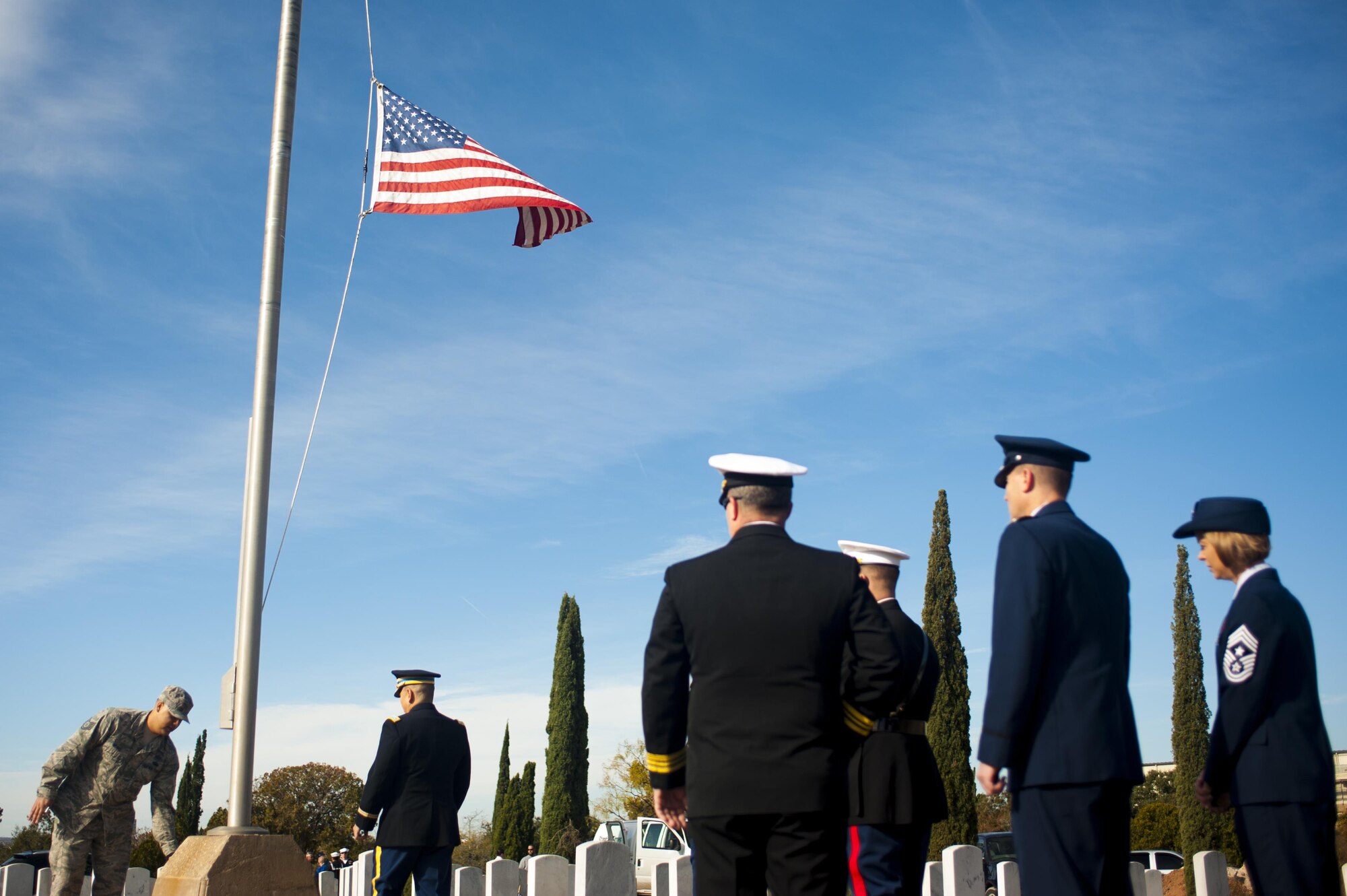 Goodfellow Air Force Base members stand beneath an American flag while practicing the laying of the wreaths around the flag’s base for Wreaths Across America at Belvedere Cemetery, San Angelo, Texas, Dec. 17, 2016.  Wreaths representing all services were placed at the flagpole. (U.S. Air Force photo by Senior Airman Scott Jackson/released)