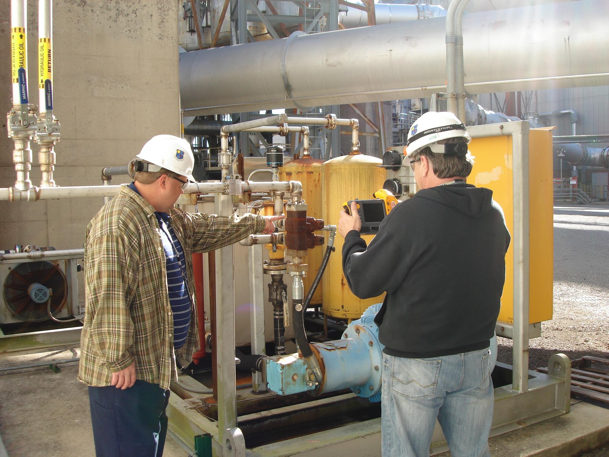 Dan Henley, infrared program lead (left), and Mike Rainey, Condition Based Maintenance outside machinist (right), take infrared temperature readings on a hydraulic unit in the Engine Test Facility A-Plant. This and other measures are taken as part of the Asset Health Assurance Program to ensure that equipment and infrastructure at AEDC are performing as needed. (AEDC photo)