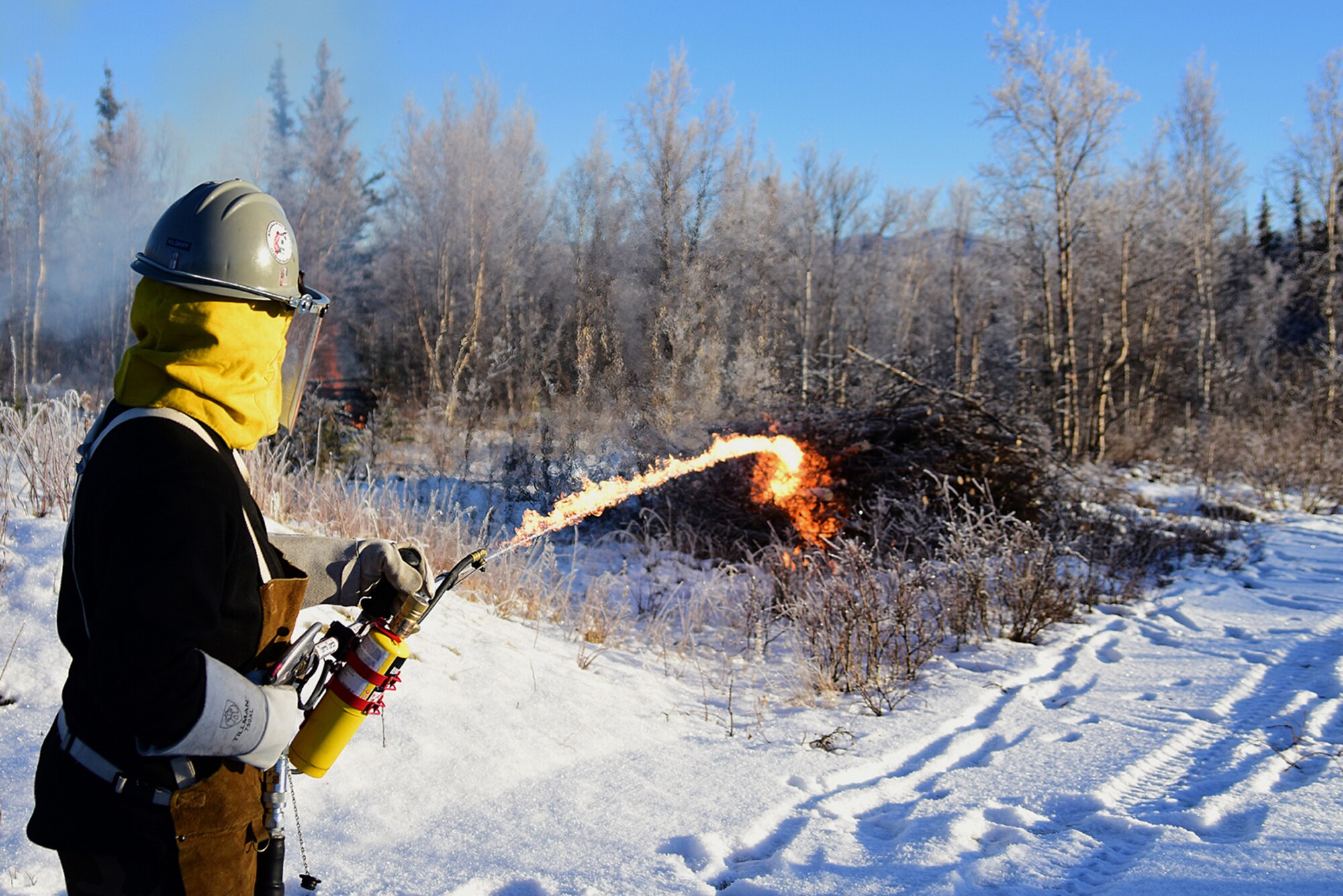 Bureau of Land Management Bureau of Land Management Alaska Fire Service specialist Matt Kilgriff shoots a stream of flaming gel from the Terra Torch to burn piles of brush and trees as part of a prescribed burn project in U.S. Army Alaska’s Donnelly Training Area near Fort Greely Nov. 4, 2016. The piles were created by U.S. Army Alaska hand crews working to remove dead and decaying vegetation and black spruce in an effort to reduce the chances of a wildfire on military lands. AFS provides wildland fire management for 1.6 million acres of military withdrawn public land under an interagency service agreement with U.S. Army Alaska. (Army photo/John Pennell)