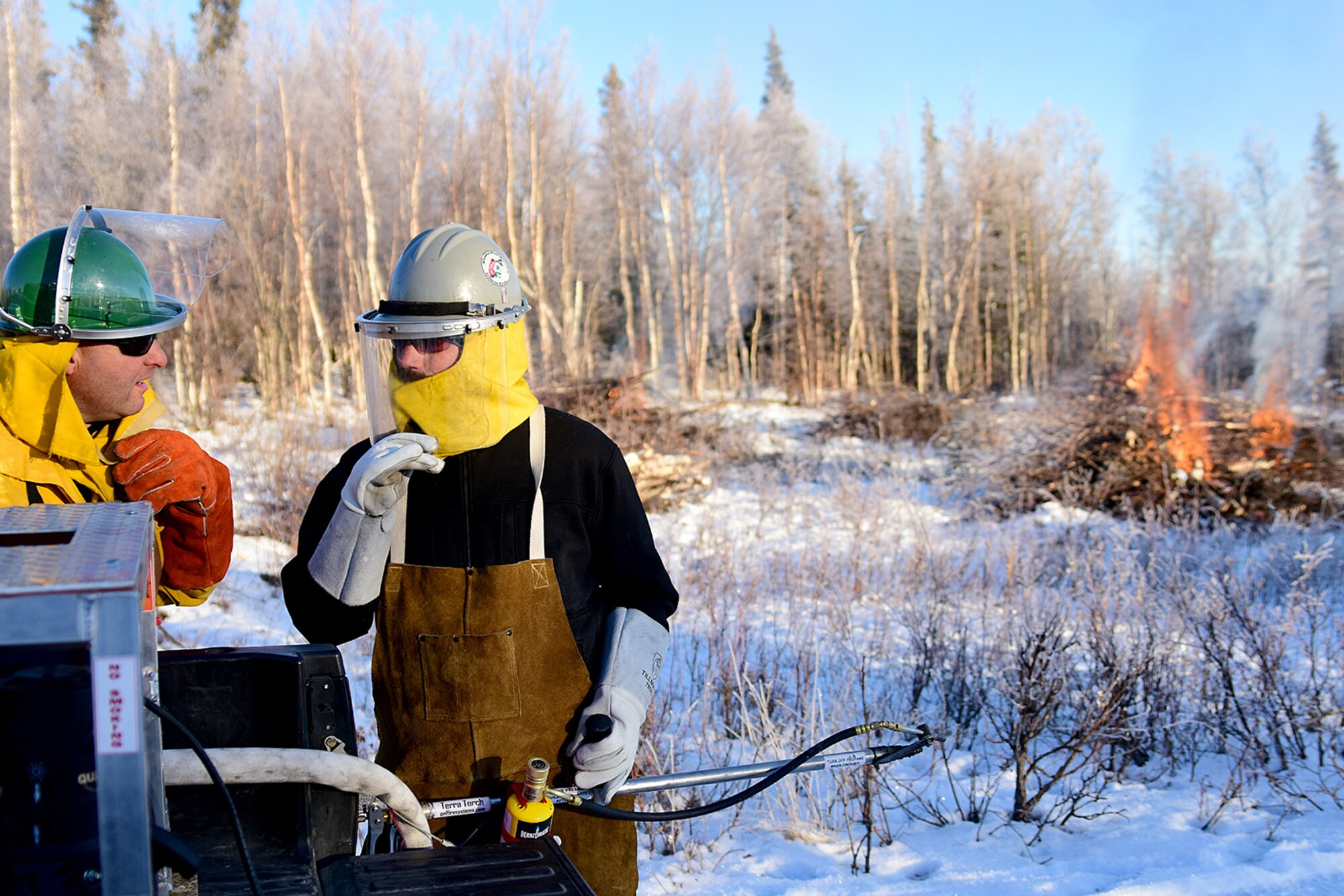 Bureau of Land Management Bureau of Land Management Alaska Fire Service specialists Bob Schober (green helmet) and Matt Kilgriff discuss tactics for burning piles of brush as part of a prescribed burn project in U.S. Army Alaska’s Donnelly Training Area near Fort Greely Nov. 4, 2016. The piles were created by U.S. Army Alaska hand crews working to remove dead and decaying vegetation and black spruce in an effort to reduce the chances of a wildfire on military lands. AFS provides wildland fire management for 1.6 million acres of military withdrawn public land under an interagency service agreement with U.S. Army Alaska. (Army photo/John Pennell)