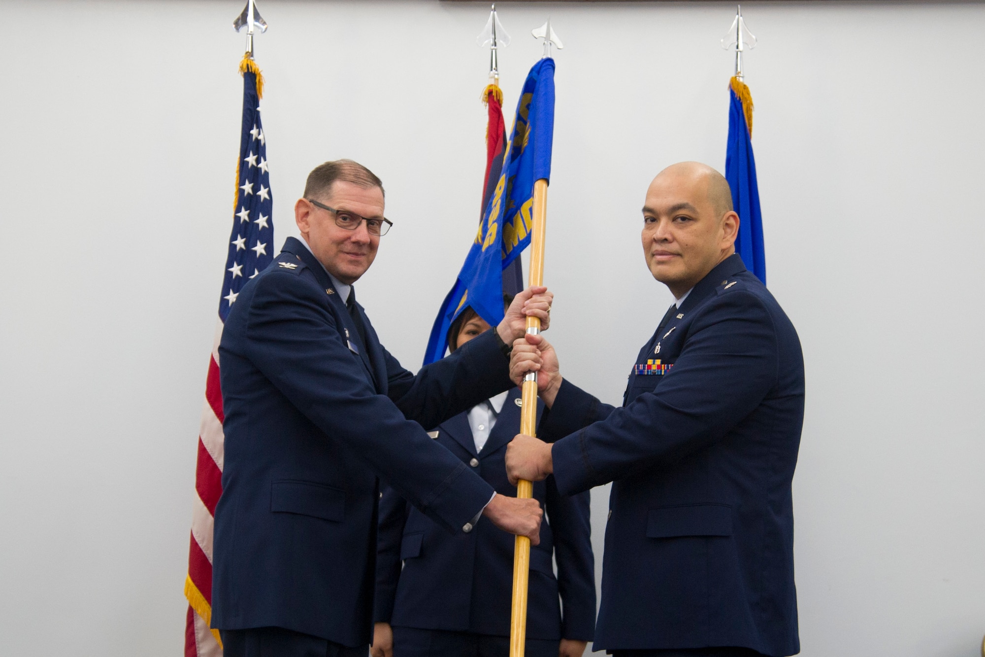 U.S. Air Force Col. Kenneth Lute, 624th Regional Support Group commander, passes the 624th Aerospace Medicine Flight’s guidon to the incoming commander Lt. Col. John Tudela during an assumption of command ceremony Dec. 11, 2016 at the Sunrise Conference Center, Andersen Air Force Base, Guam. The 624th AMDF supports the 624th Regional Support Group’s mission to deliver mission essential capability through combat readiness, quality management and peacetime deployments in the Pacific area of responsibility. (U.S. Air Force photo by Master Sgt. Theanne Herrmann)
