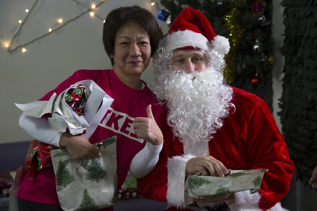 A caregiver poses for a photo with Santa Claus during a Christmas visit at the Reimei no Sato home for the disabled Dec. 16 in Ishikawa, Okinawa, Japan. Reimei no Sato provides care for adults with special day-to-day living needs. During the visit, Marines from Camp Hansen delivered Christmas gifts provided by the Marine Officers Spouses Club and spent time spreading Christmas cheer with the residents. The Marines are with 12th Marine Regiment, 3rd Marine Division, III Marine Expeditionary Force. (U.S. Marine Corps photo by Cpl. Janessa K. Pon)