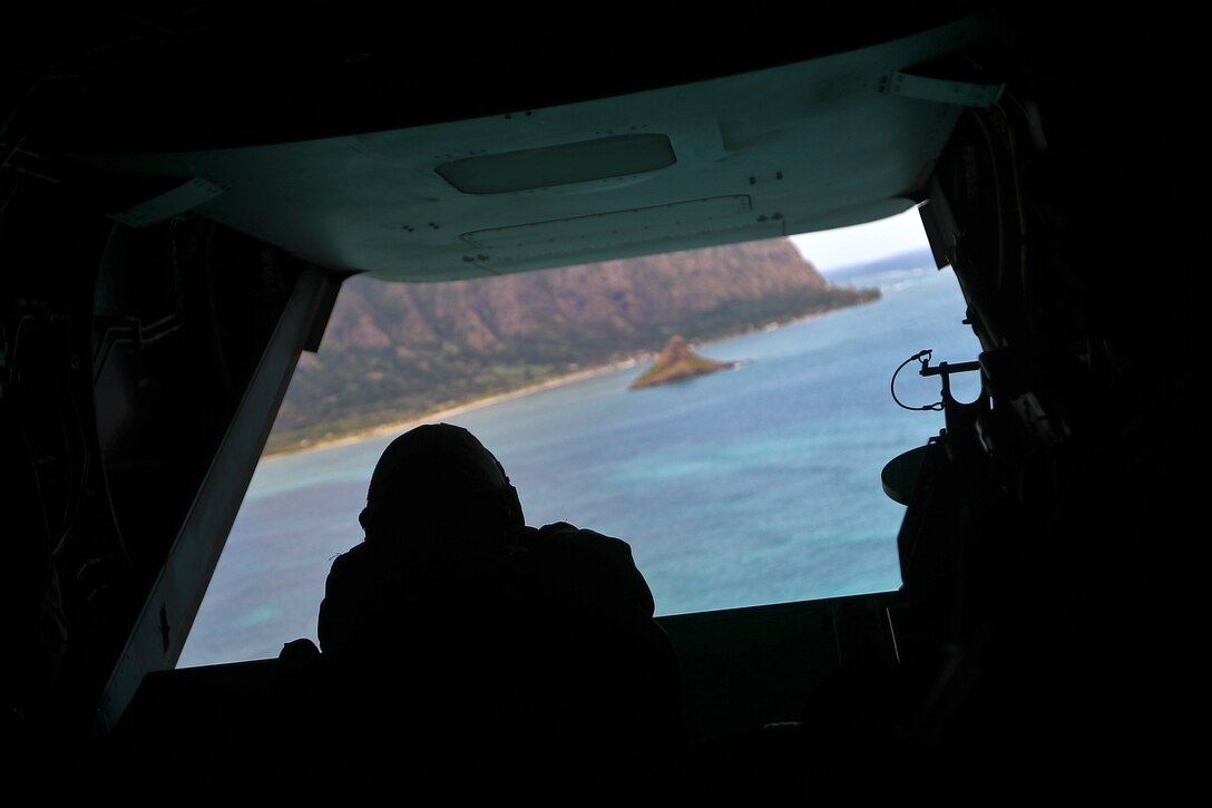 A Marine crew chief looks out the back of an MV-22 Osprey during a simulation of Operation Gothic Serpent, a 1993 operation in Somalia, over Kaneohe Bay, Hawaii, Dec. 10, 2016. The crew chief is assigned to Marine Medium Tiltrotor Squadron 268. Marine Corps photo by Cpl. Aaron S. Patterson