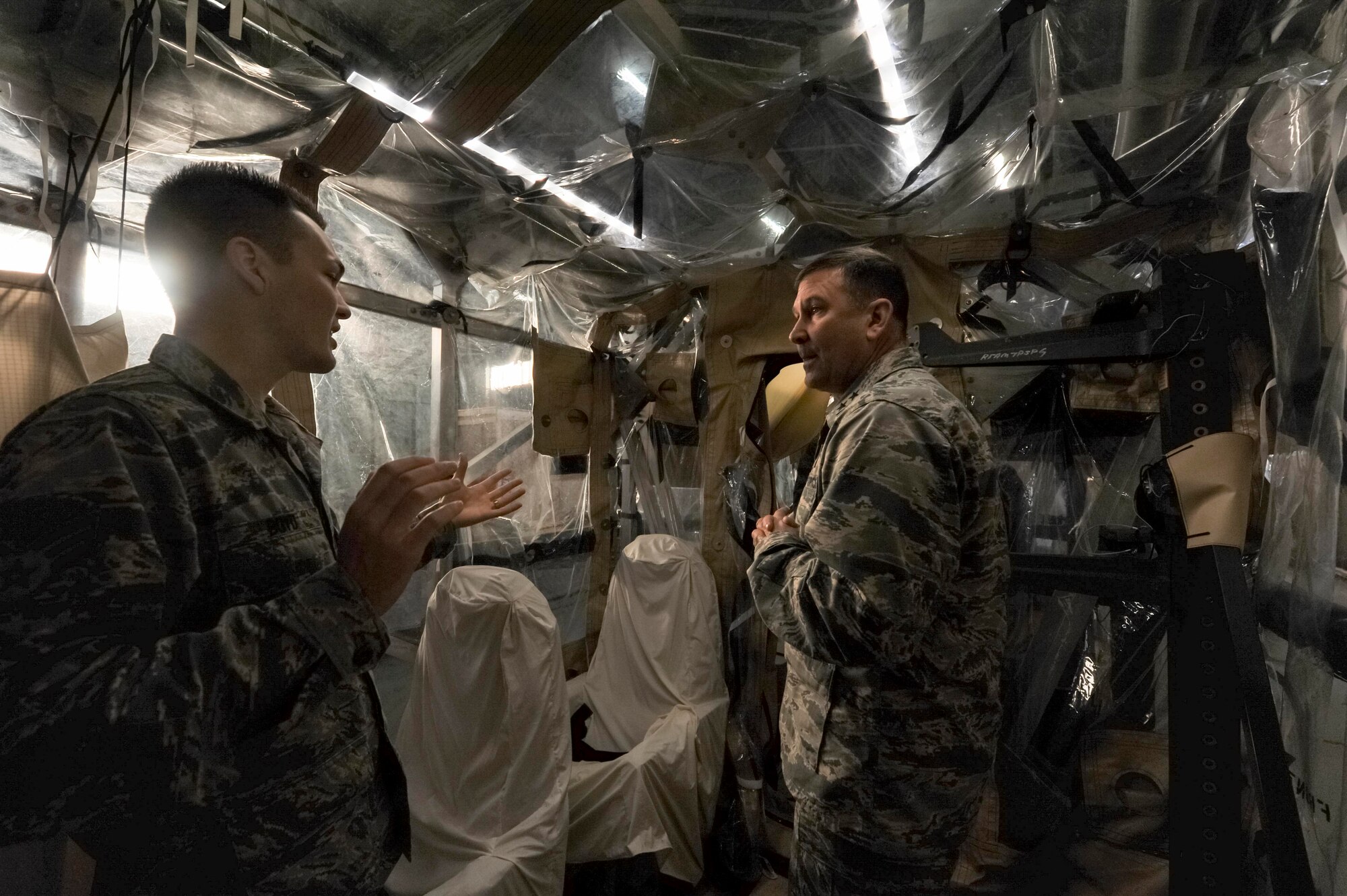 Senior Airman Peter Boyd, 628th Medical Group Bioenvironmental Engineering Flight biomedical maintenance technician, left, explains how the Transportation Isolation System works to Maj. Gen. Christopher J. Bence, U.S. Air Force Expeditionary Center commander, right, at the TIS hangar here, Dec. 15, 2016. While at Joint Base Charleston, Bence toured Team Charleston's facilities to get a first-hand look at joint operations. 