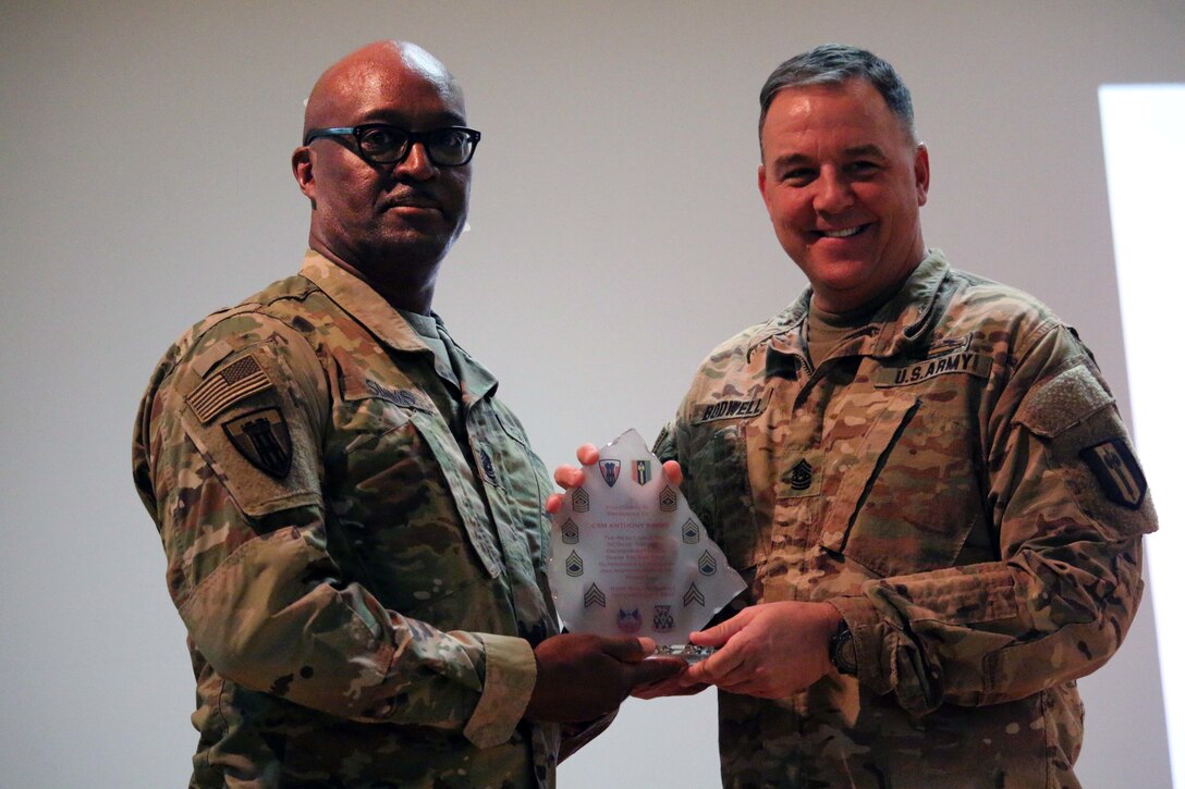 Command Sgt. Maj. Stephen M. Bodwell, 368th Eng. Bn. presents Command Sgt. Maj. Anthony Simms with a battalion award as a token of appreciation for his words of encouragement to Task Force Granite Soldiers participating in the Non-Commissioned Officer Induction Ceremony held at Camp Arifjan, Kuwait, Nov. 29, 2016. The ceremony consisted of approximately 106 Soldiers from 312th Eng. Co, 389th Eng. Co., 461st Eng. Co, 475th Eng. Co., Headquarters and Headquarters Co. and Forward Support Co. of 368th Eng. Bn. (U.S. Army photo by Capt. Maria Mengrone/Released)