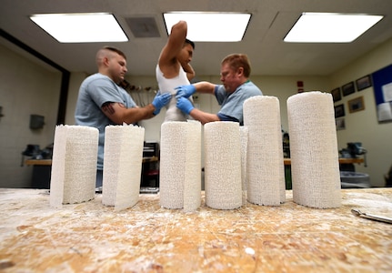 Staff Sgt. Devin Rudd, (left) a student in the orthotics program, and Lawrence New, (right) a 59th Medical Wing orthotist and orthotics instructor, use plaster to create a mold for a body jacket orthoses at the Wilford Hall Ambulatory Surgical Center, Joint Base San Antonio-Lackland, Texas, Aug. 24, 2016. Staff Sgt. Kenneth Rivera, (center), is also a student in the orthotics program and served as the patient for the lesson. (U.S. Air Force photo/Staff Sgt. Jerilyn Quintanilla)