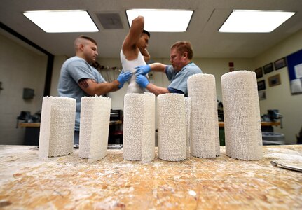 Staff Sgt. Devin Rudd, (left) a student in the orthotics program, and Lawrence New, (right) a 59th Medical Wing orthotist and orthotics instructor, use plaster to create a mold for a body jacket orthoses at the Wilford Hall Ambulatory Surgical Center, Joint Base San Antonio-Lackland, Texas, Aug. 24, 2016. Staff Sgt. Kenneth Rivera, (center), is also a student in the orthotics program and served as the patient for the lesson. (U.S. Air Force photo/Staff Sgt. Jerilyn Quintanilla)