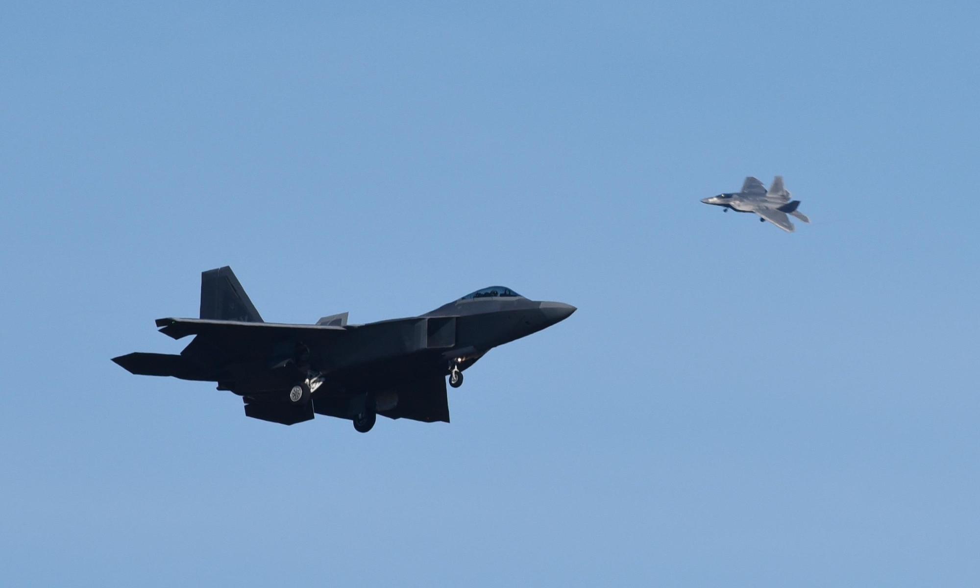 Two U.S. Air Force F-22 Raptors from Tyndall Air Force Base, Fla., fly over the base during Checkered Flag 17-1, Dec. 16, 2016. The integration training pilots receive during exercises like Checkered Flag ensure teams of different capabilities can seamlessly integrate and work together in a real-world combat situation utilizing fifth- and fourth-generation air assets. (U.S. Air Force photo by Staff Sgt. Alex Fox Echols III/Released)