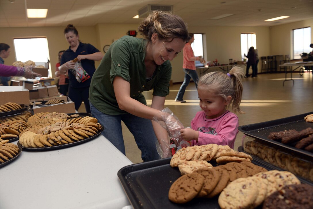 Amber Hoffman, the spouse of Capt. Jeffery Hoffman from the 28th Bomb Wing Judge Advocate Office, and her daughter bag cookies for Airmen in the Box Elder Event Center, S.D., Dec. 14, 2016. The Enlisted Spouses' Club and the Officer and Civilian Spouses' Club baked and collected more than 11,000 cookies for Ellsworth Airmen staying in the dorms, doubling last year’s goal of 5,000 cookies, for their 5th annual holiday cookie drive. (U.S. Air Force photo by Airman 1st Class Donald C. Knechtel)