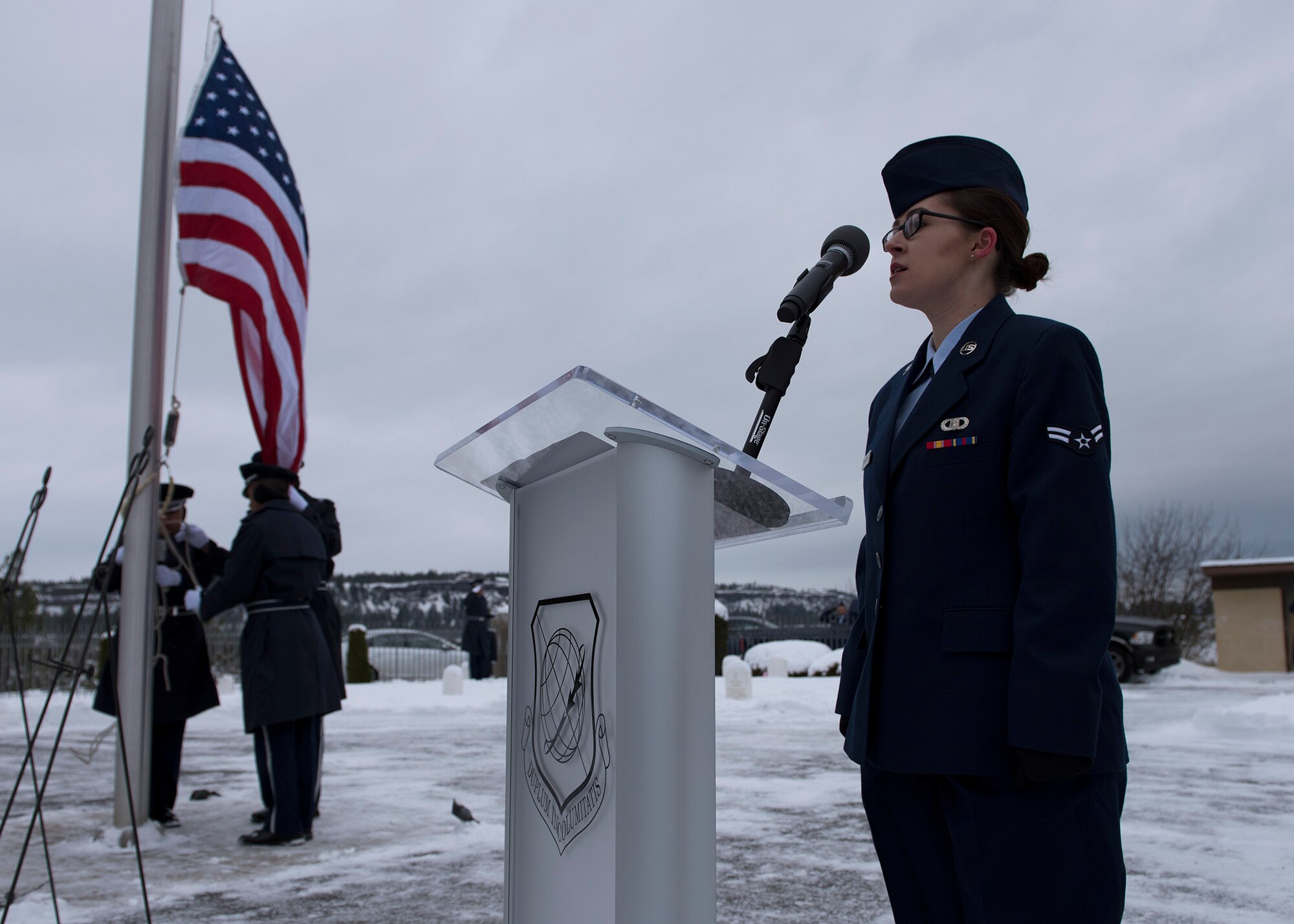 Airman 1st Class Sydney Silvester, 92nd Operations Support Squadron weather forecaster, sings the U.S. national anthem at the start of an official ceremony at Fort George Wright Cemetery Dec. 19, 2016, near Spokane, Washington. Service members braved freezing temperatures to honor the memory of the service members buried at the site. (U.S. Air Force Photo/Airman 1st Class Ryan Lackey)