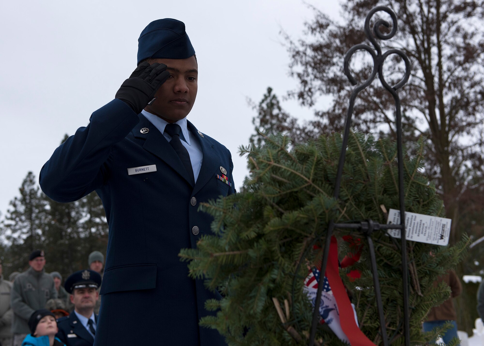 Airman 1st Class Kamuzu Burnett, 92nd Operations Support Squadron air crew flight equipment journeyman, salutes a wreath presented in remembrance to United States Air Force deceased service members during a ceremony at Fort George Wright Cemetery Dec. 19, 2016, near Spokane, Wash. Wreaths were presented in remembrance of the deceased of each U.S. military service branch. (U.S. Air Force photo/Airman 1st Class Ryan Lackey)