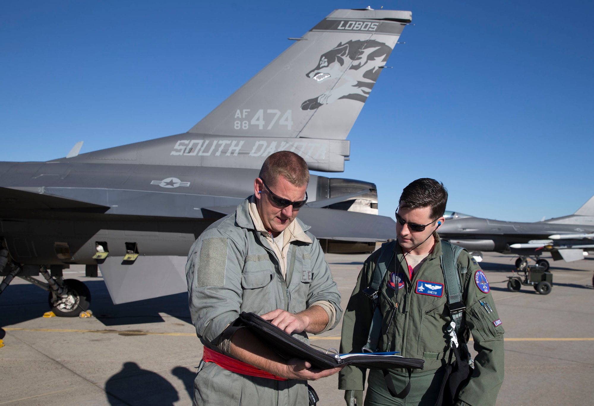SIOUX FALLS, S.D. - Capt. Patrick Cheto Harrington, Air Force F-16 pilot assigned to the 378th Fighter Squadron, Truax Field, Wis., and Senior Master Sgt. Shawn Emerson, 114th Aircraft Maintenance Squadron crew chief, looks over the aircraft forms assigned to an F-16 aircraft. With the Total Force Integration program, Harrington is one of many active duty Airmen who are assigned to Air National Guard units around the country. (Photo by High-G Productions/released)