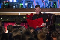U.S. Marine Corps Cpl. Camden E. Bettey, a musician assigned to the 2nd Marine Aircraft Wing (MAW) Band, reads “’Twas the Night before Christmas” to children during the 2nd MAW Band holiday concert at Marine Corps Air Station Cherry Point, N.C., Dec. 18, 2016. The 2nd MAW Band hosted the concert to bring both military and the local community together during the holidays. 
