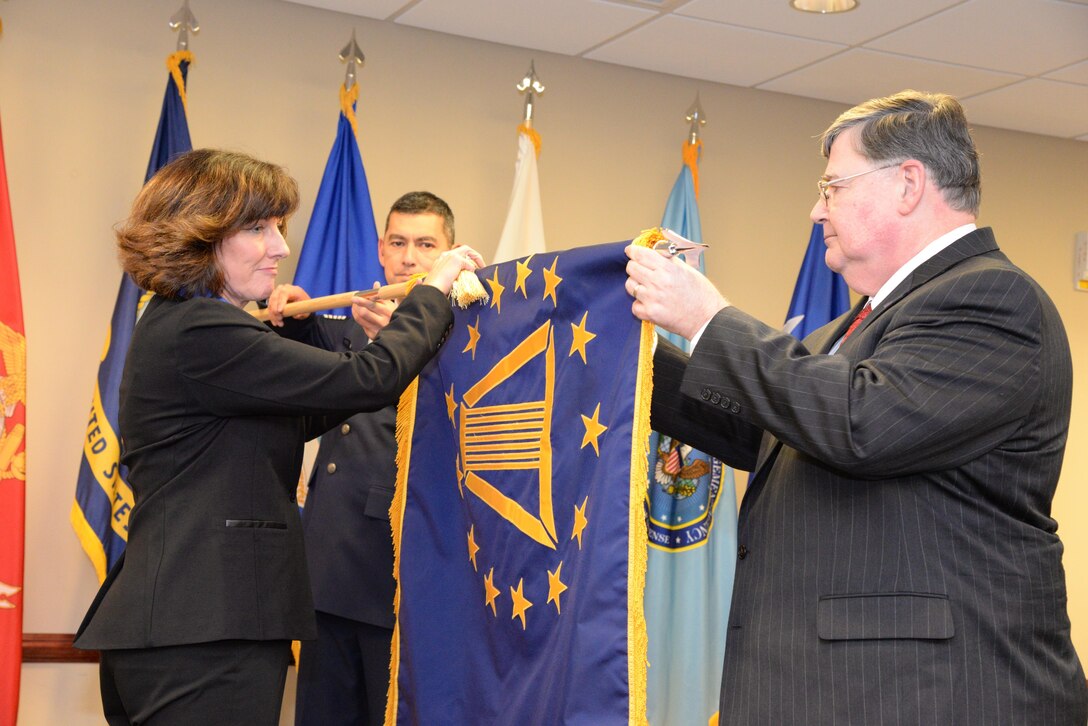 Pam Conklin, executive director of Defense Contract Management Agency Financial & Business Operations; and Timothy Callahan, executive director of DCMA Contract, ceremonially retire Jim Russell’s Senior Executive Service flag at a Dec. 19 ceremony at Fort Lee, Virginia. Russell retired as the agency’s deputy director after 36 years of federal service. (DCMA photo by Stephen Hickok)