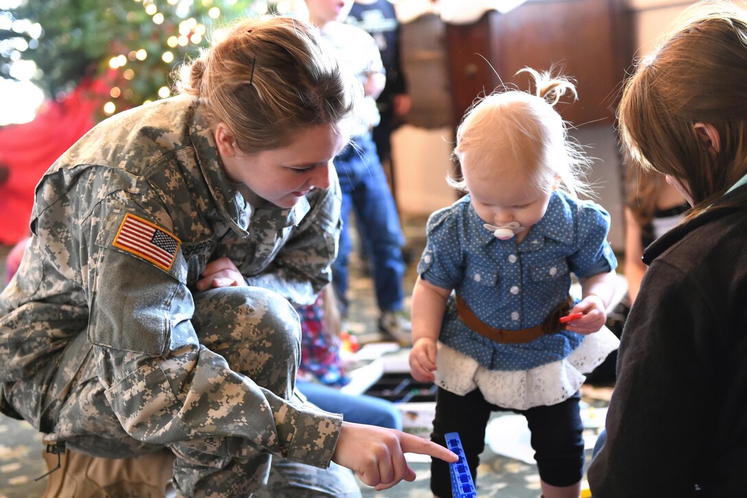 U.S. Army Private Pfc. Emily Shepperd, 316th Psychological Operations Company, helps Emma Thompson with a board game during their annual family day in Kokomo, Ind., Dec. 10, 2016. The event included a special Welcome Home Warrior-Citizen ceremony for returning deployers and a promotion ceremony in addition to holiday festivities for Soldiers and their families. (U.S. Air Force photo/Tech. Sgt. Benjamin Mota)