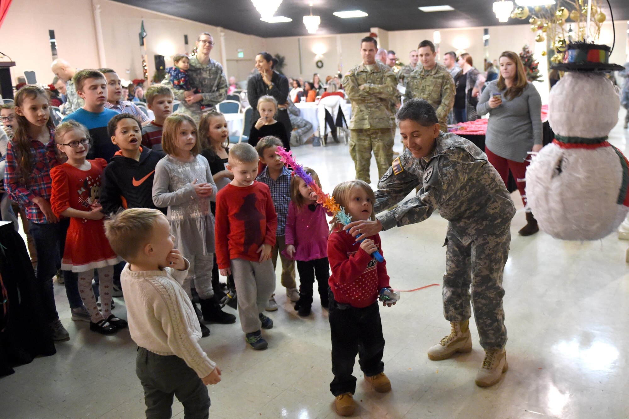 U. S. Army Sgt. 1st Class Ana Doody, 316th Psychological Operations Company training noncommissioned officer in charge, manages children attempting to strike a piñata during their annual family day in Kokomo, Ind., Dec. 10, 2016. During the event children also had an opportunity to visit Santa and receive gifts. (U.S. Air Force photo/Tech. Sgt. Benjamin Mota)