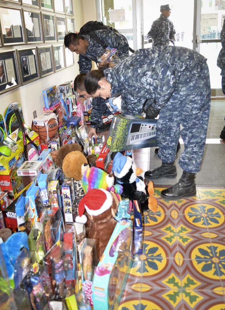 Students pick up toys in Anderson Hall at the Medical Education and Training Campus, or METC, on Joint Base San Antonio-Fort Sam Houston following a ceremony to wrap up METC's fifth annual toy drive. Anderson Hall was named after Petty Officer 3rd Class Christopher Anderson who was killed in action Dec. 4, 2006, in Ramadi, Iraq, while serving with the 1st Battalion, 6th Marines. Every year, Sailors at METC organize a toy drive in Anderson's honor to collect donations for Toys for Tots. 