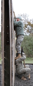 Spc. Victoria Lowery stands on her husband’s – Spc. Chad Lowery – shoulder to climb over a wall obsticle during the confidence course at the first Guardian Challenge at Joint Base San Antonio-Camp Bullis Dec. 9. Both are assigned to Headquarters Support Company, Headquarters, Headquarters Battalion, U.S. Army North (Fifth Army) at JBSA-Fort Sam Houston.
