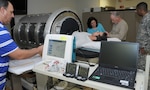 (From left) Gary Muniz, Carmen Hinojosa-Laborde and Victor “Vic” Convertino from the U.S. Army Institute of Surgical Research at Joint Base San Antonio-Fort Sam Houston place monitors on a volunteer in the lower body negative pressure chamber to collect physiological data as part of a research protocol as Lt. Col. Robert Carter (right) from USAISR looks on.